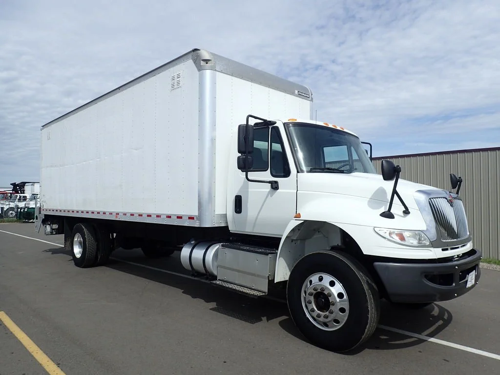 A white box truck parked in a lot with a gray sky overhead.