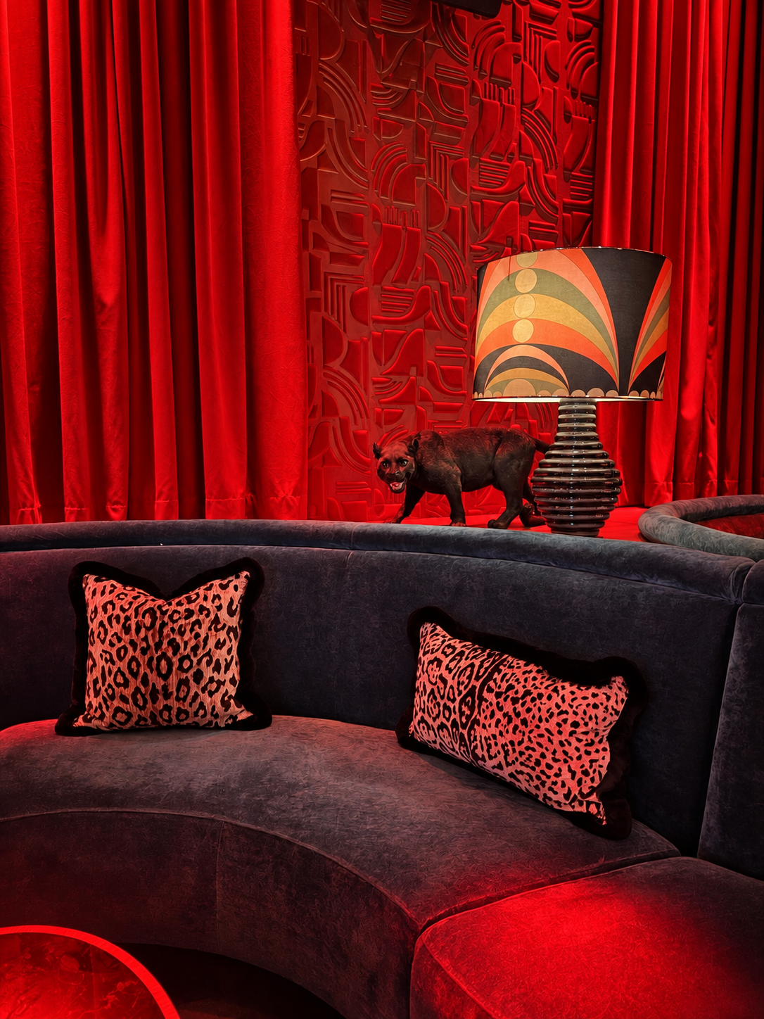 Red curtains, patterned lamp, and velvet seating at Amazónico’s Selva Lounge