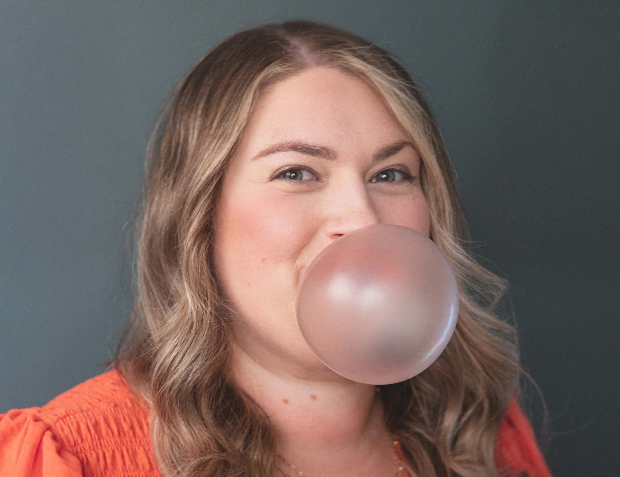 Kristin Geosits, co-host of the Have You Tried Being Rich podcast, blowing a bubble gum bubble in promotional photography for the personal finance podcast.
