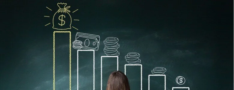 A person looking at a chalkboard with a bar graph showing decreasing coins and dollar bills, with a gold money bag icon at the highest point.