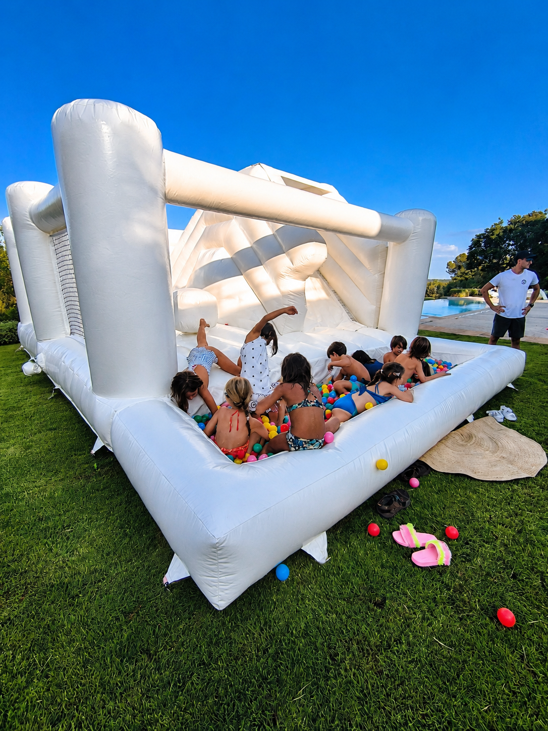 Children enjoying Norivan white bouncy castle with ball pit and slide at a party in Artà, Mallorca