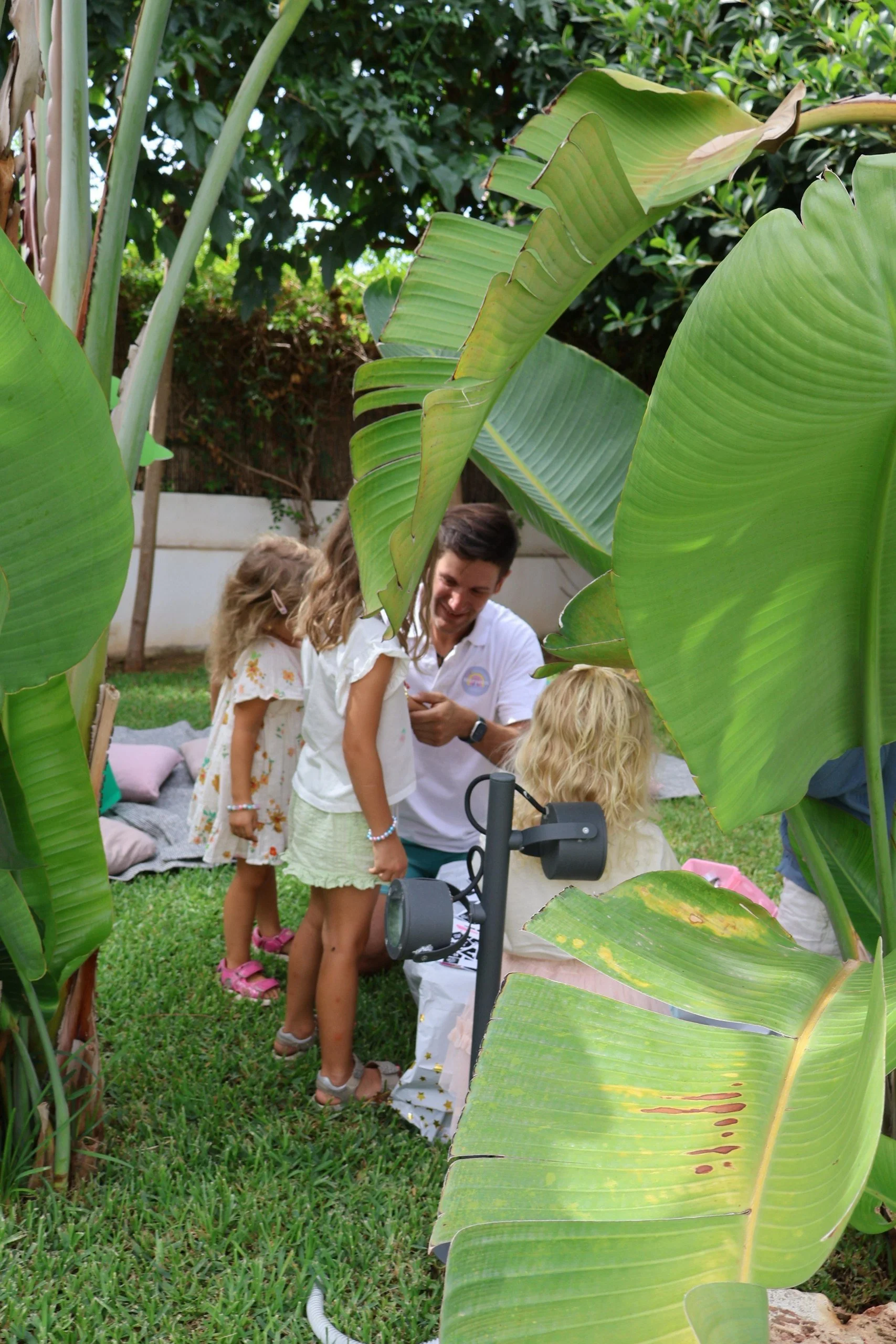 Professional kids animator Ivan applying sparkling glitter tattoos to little girls at a premium children's birthday party in Palmanova, Mallorca by Norivan Kids Entertainment.