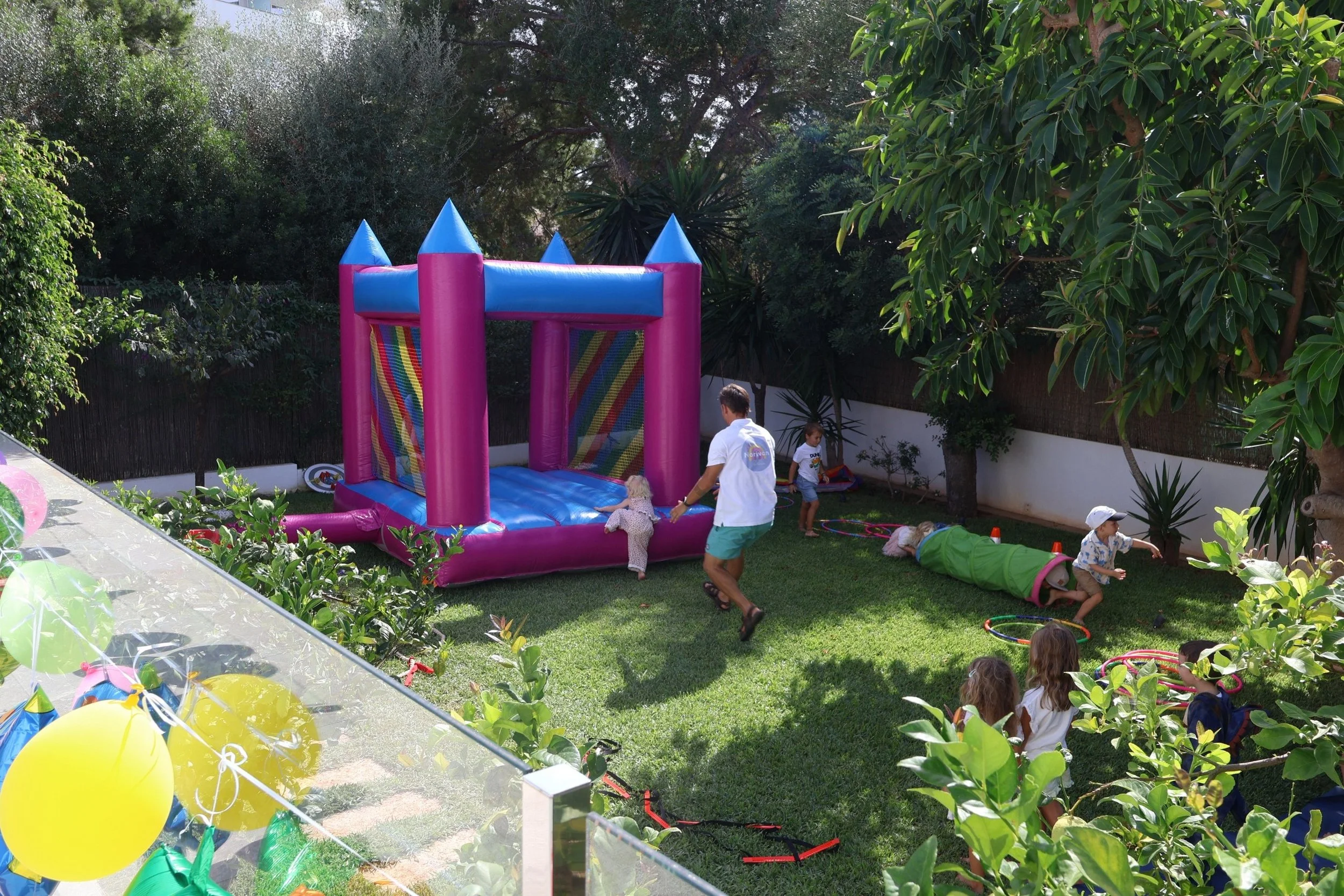 Professional kids entertainer Ivan from Norivan Kids Entertainment guiding a small toddler safely onto a mini bouncy castle at a private party in Mallorca.