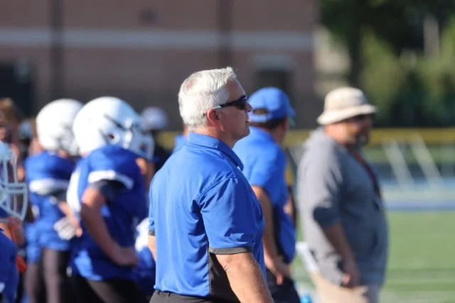 A group of Bexley Ohio OH Middle School Football football players on the field with their coach, all dressed in gear and helmets, possibly during a game or practice.