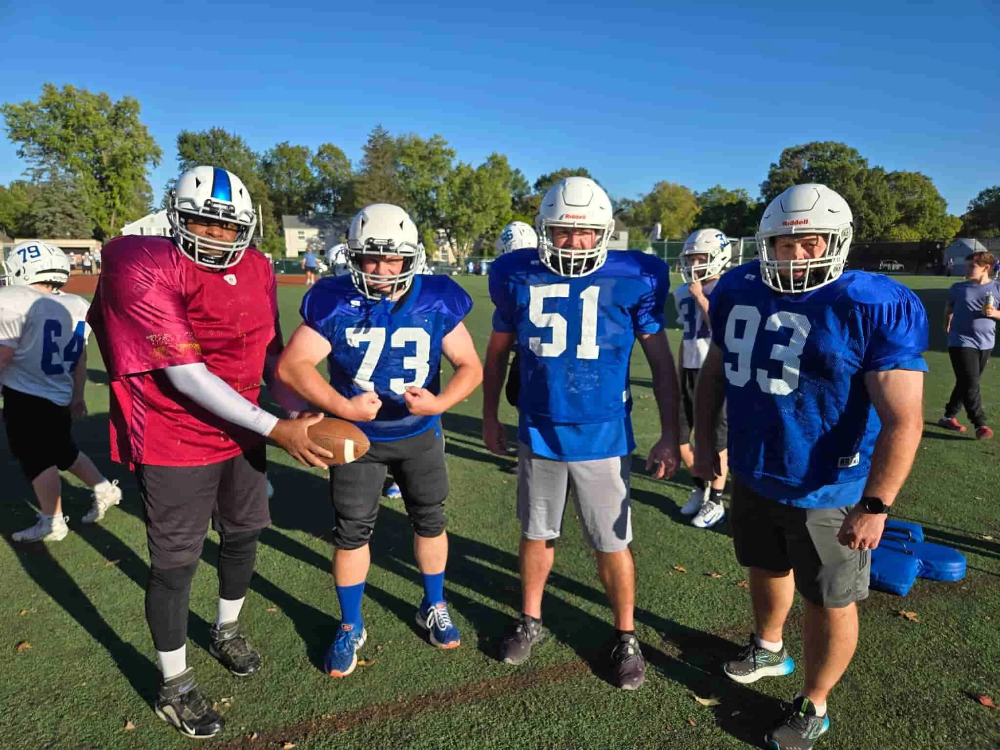 A group of football players in blue and white uniforms standing on a football field.
