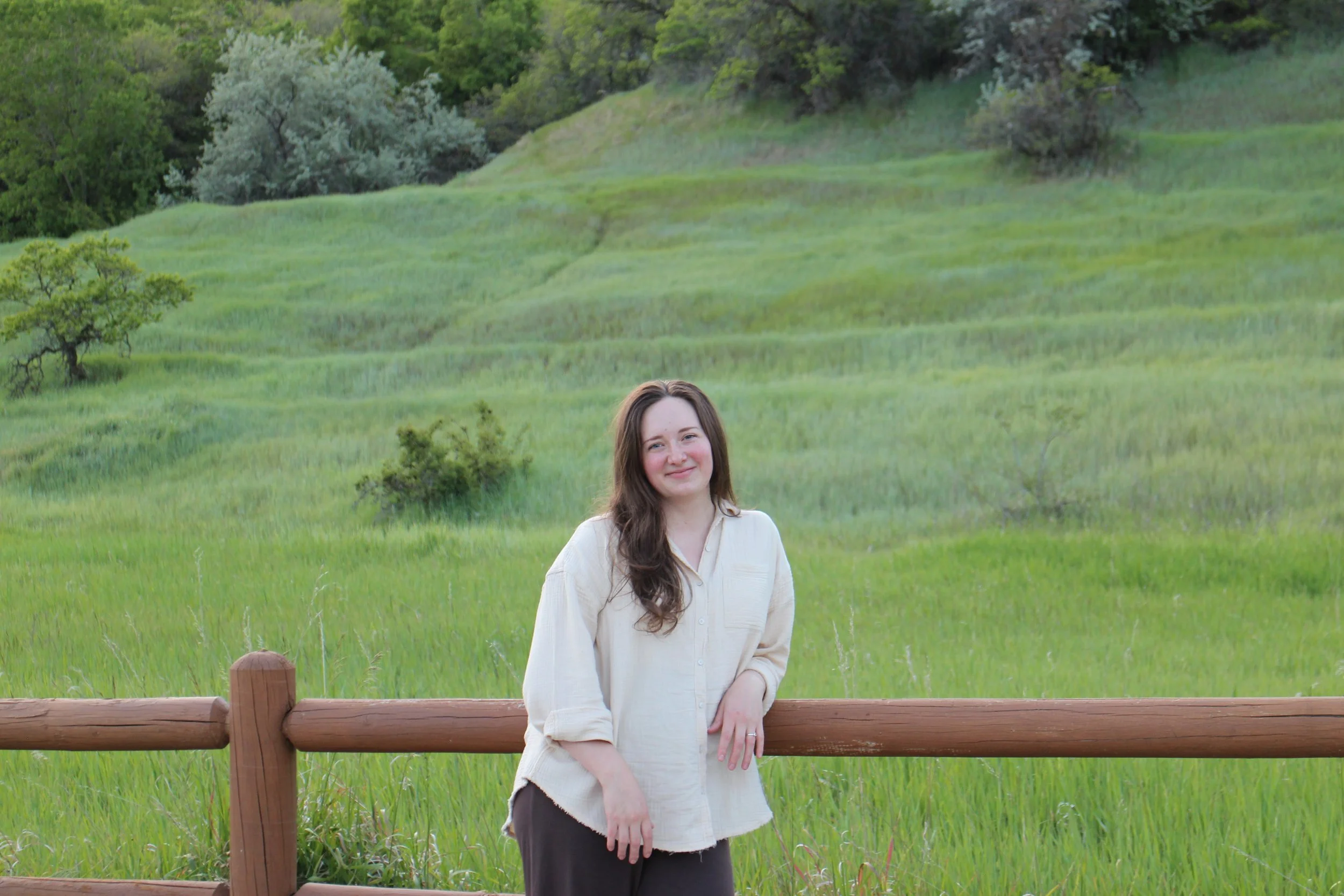 Therapist Melanie Crofts standing in a green field in Utah, representing Ascent Therapy Co. and virtual trauma and OCD therapy.