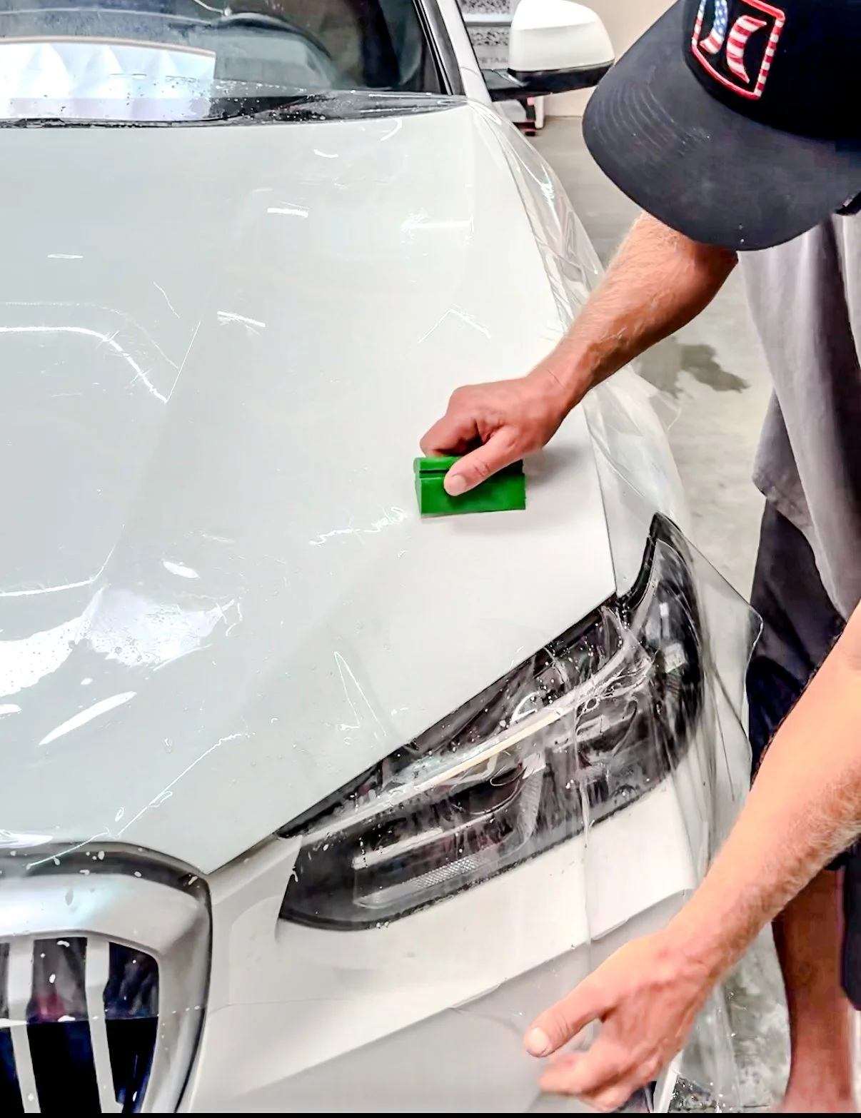 A person applying paint protection film to BMW