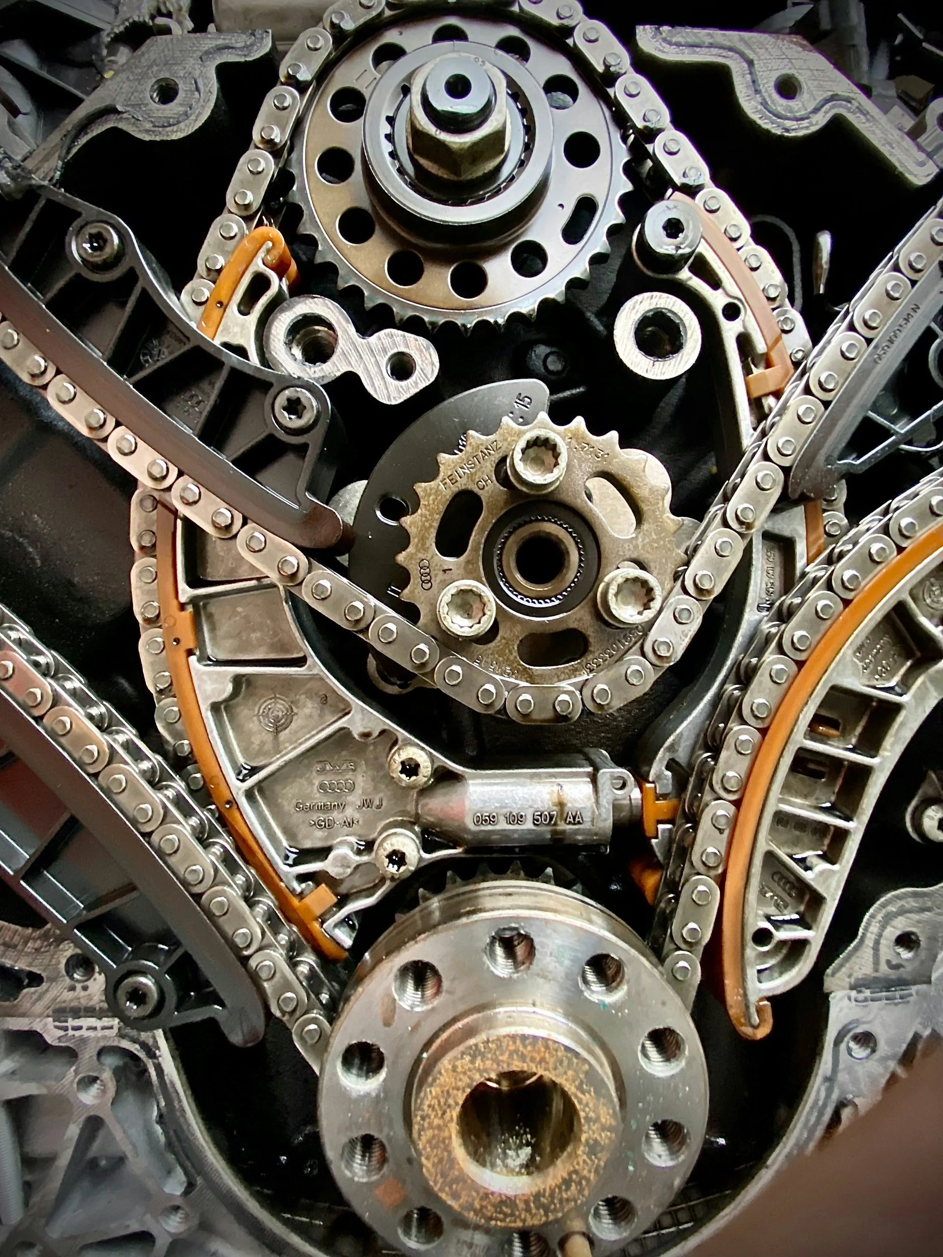 Close-up of an internal engine component with gears, chains, and metal parts.