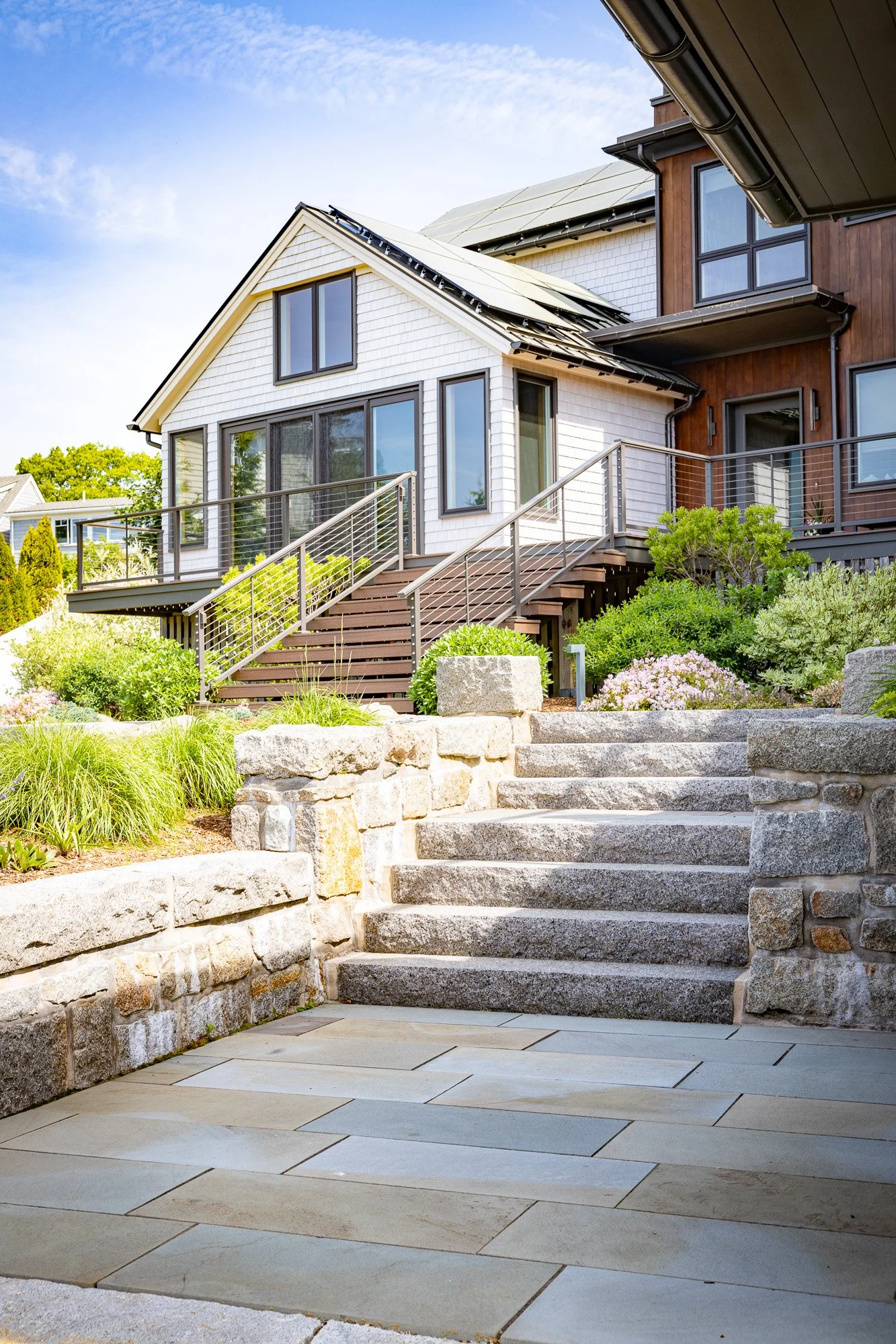 House with new solar panels on roof, front steps, landscaped garden, and stone pathway.
