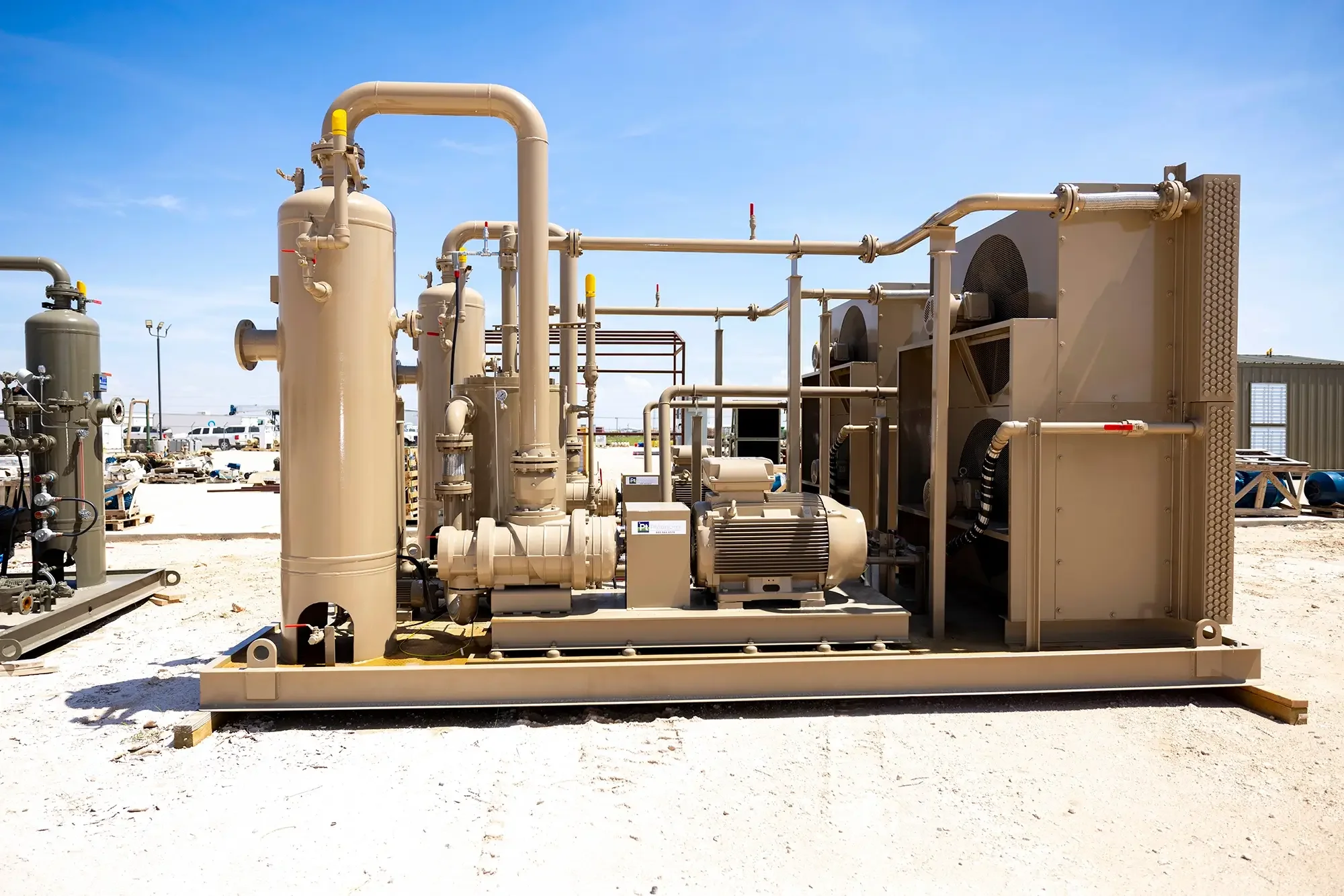 Industrial equipment with pipes, tanks, and motors set up outdoors under a clear blue sky.