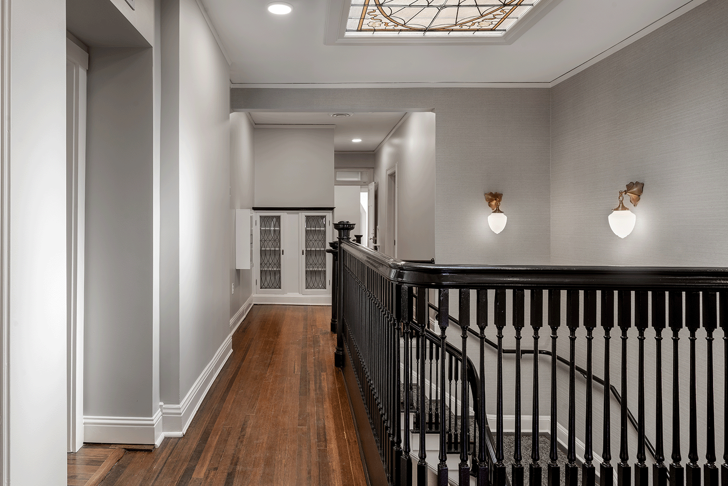 Gloss black stair-railing highlighted with delicate  wall sconces.