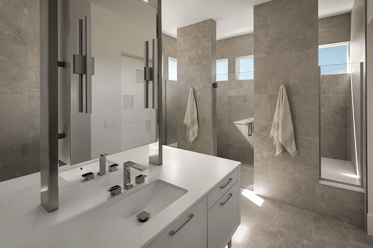 Modern bathroom with a floating vanity, warm gray stone walls and floors and a large walk-in shower.