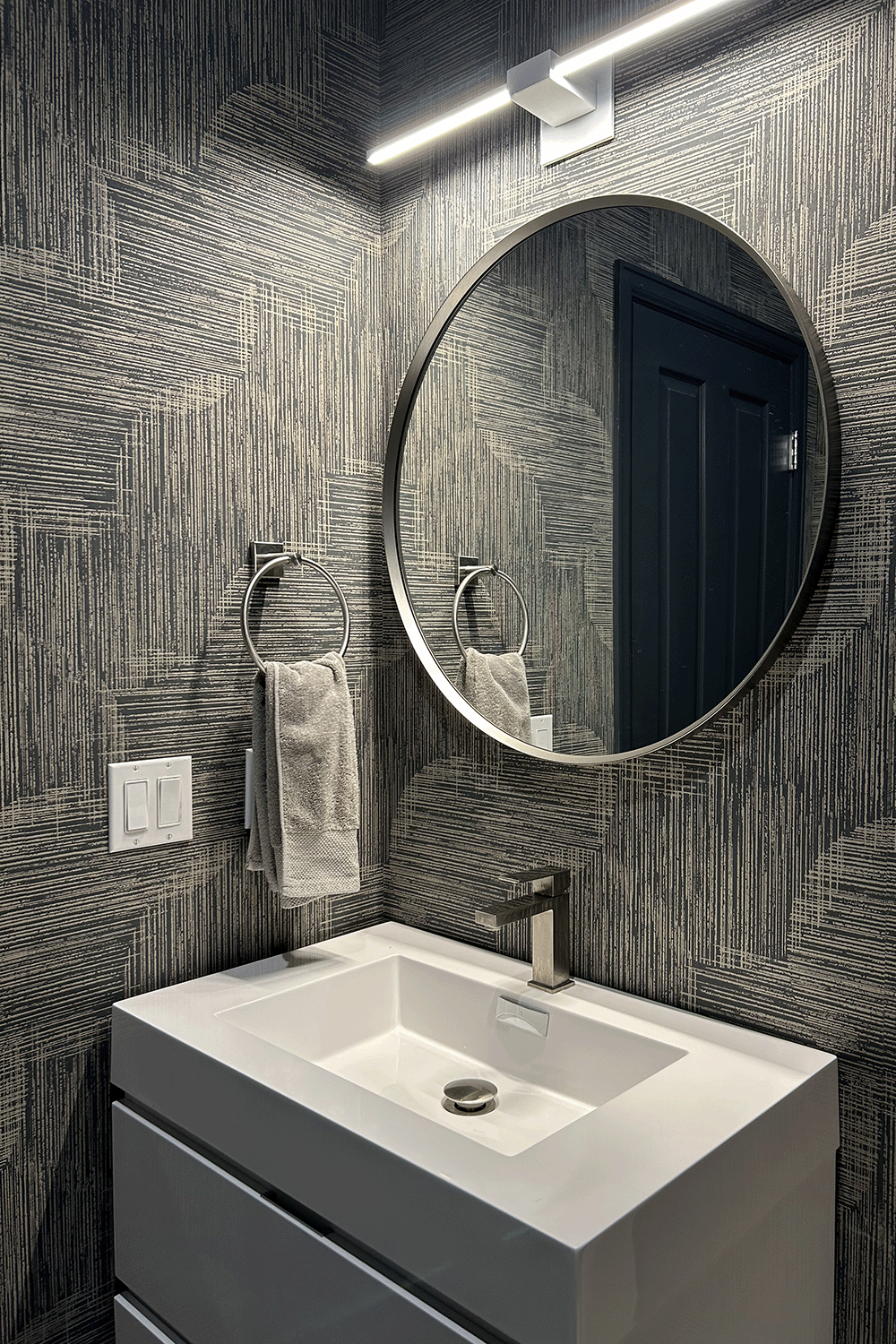 Powder bath with graphic spheres wallpaper, floating vanity and linear pendant.