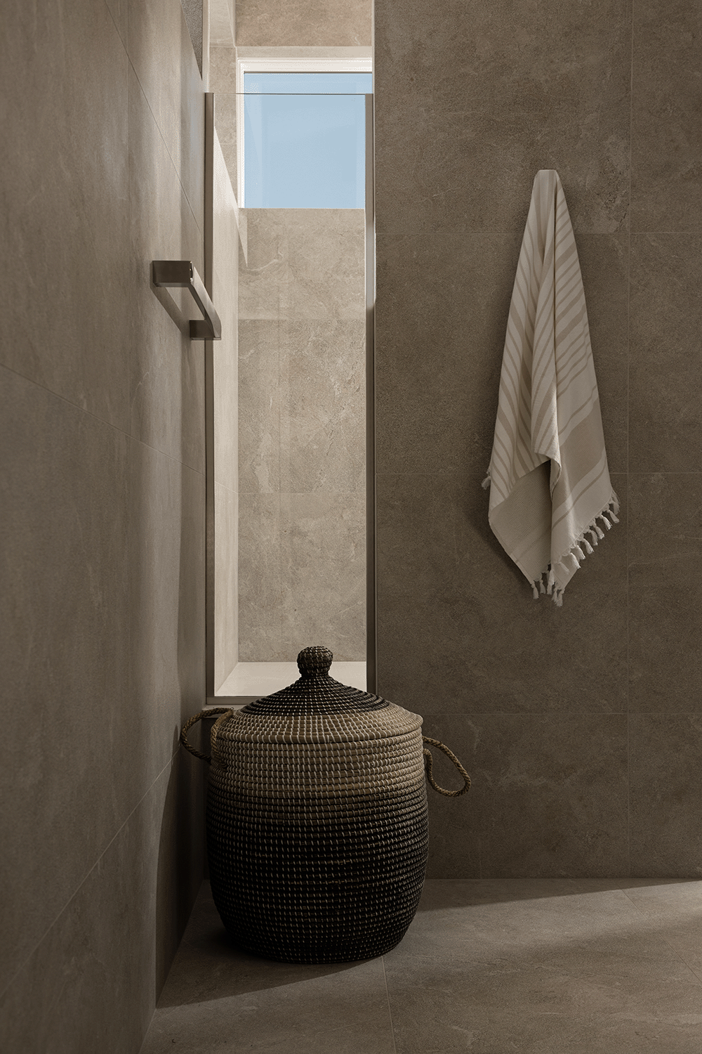 Tranquil bathroom with a woven basket and towel hanging on a robe hook.