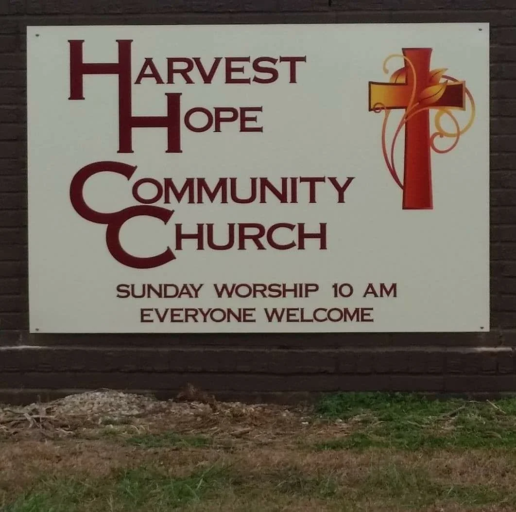Sign for Harvest Hope Community Church with a cross and decorative elements, indicating Sunday worship at 10 am and welcoming everyone.