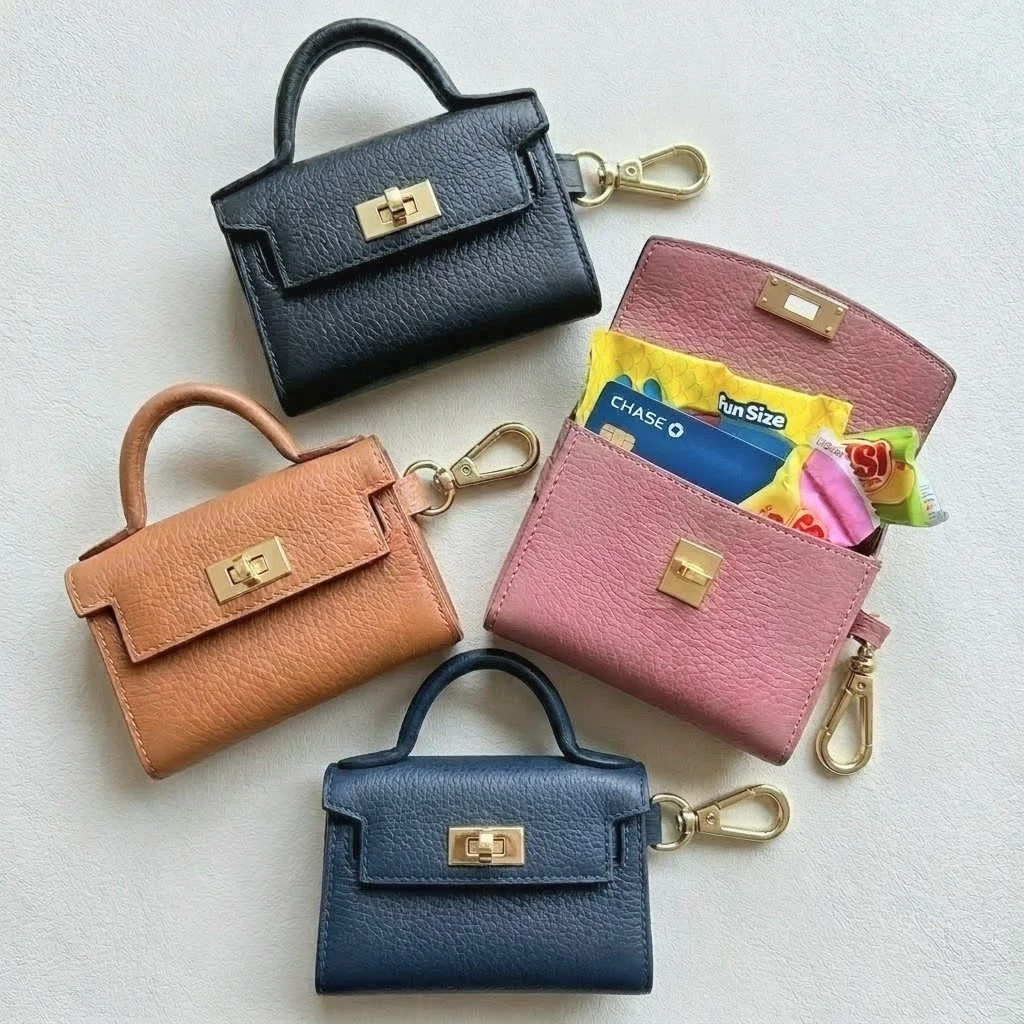 Three leather miniature keychain handbags in black, tan, and navy blue, each with a gold clasp and keychain clip, and an open pink version showing the emergency glucose and cards inside.
