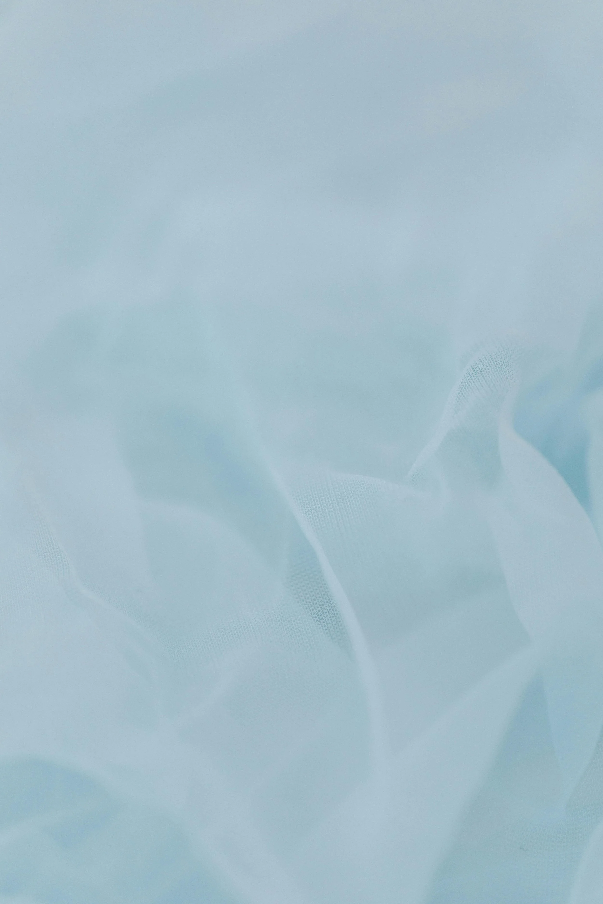 Light blue semi-transparent fabric with soft folds and subtle dotted pattern.