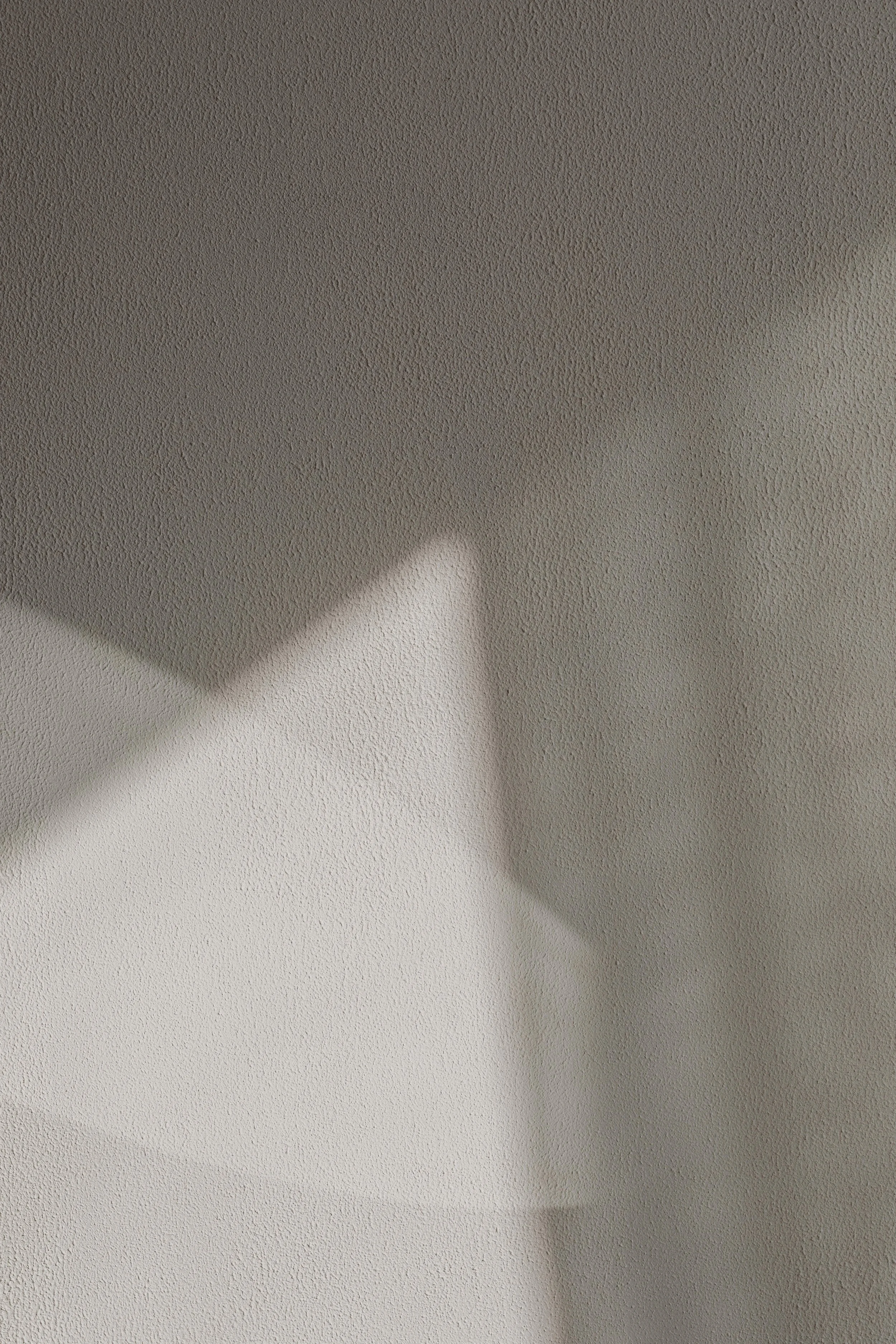 Close-up view of a textured ceiling with a shadow cast across it.