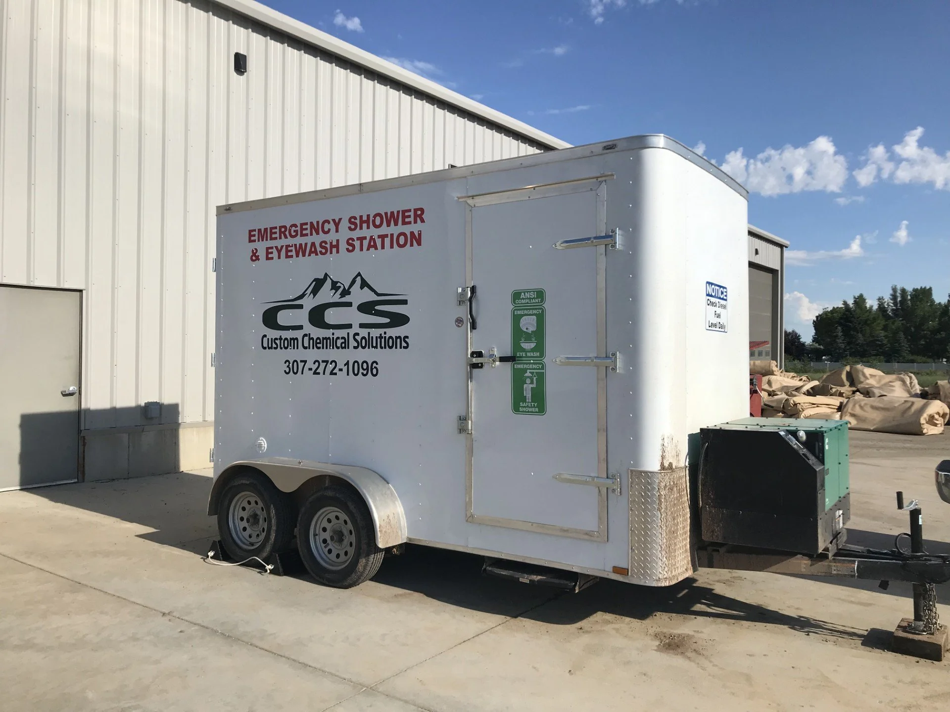 Mobile emergency shower and eyewash station trailer parked outside a building.