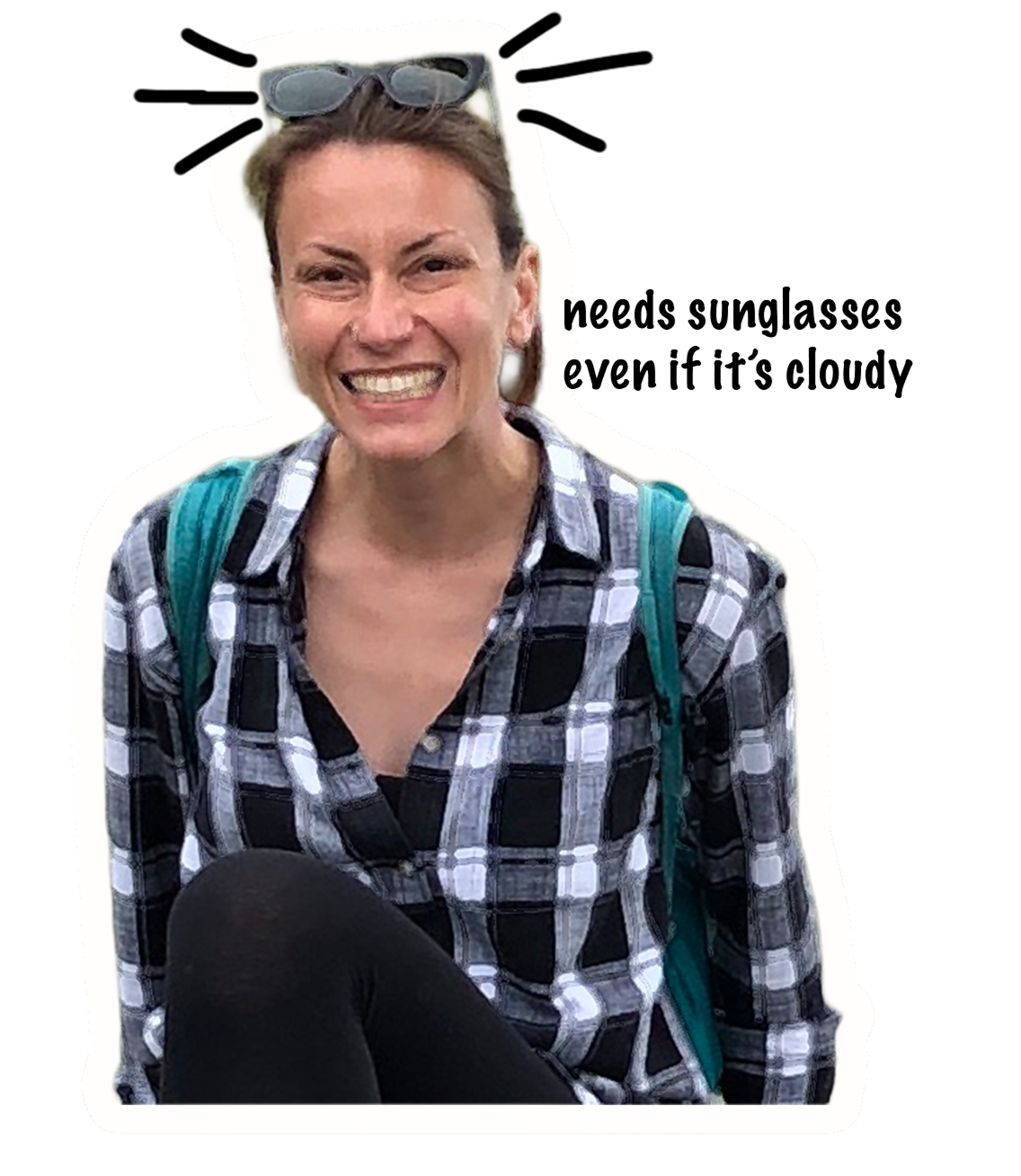 Lisa, sunglasses perched on her head, smiling broadly and squinting, wearing a black and white plaid shirt and a teal backpack, sitting outdoors.