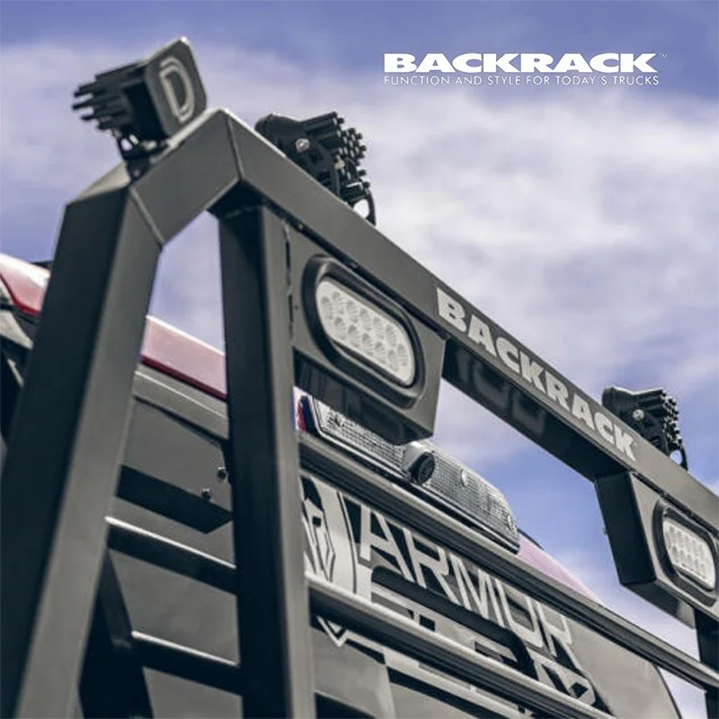 Close-up view of a fire truck with a BLACKBACK grill guard, showing lights and the word 'BACKRACK' on top, against a blue sky.