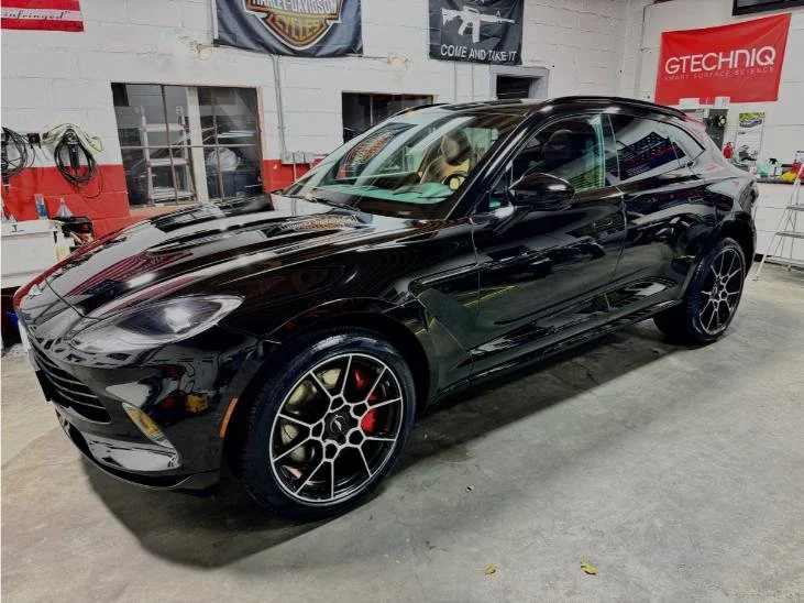 Black sports car with sleek design and black alloy wheels parked inside a garage.