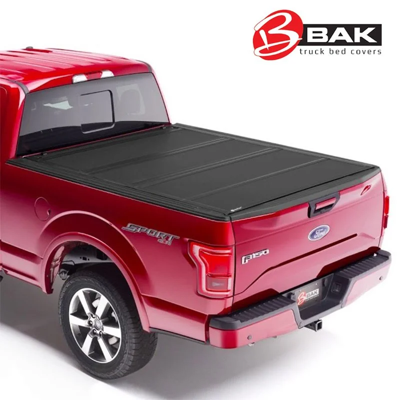 A red Ford F-150 pickup truck with a black BAK truck bed cover installed on the bed. The truck is shown from the rear and side. The BAK logo is visible in the upper right corner.