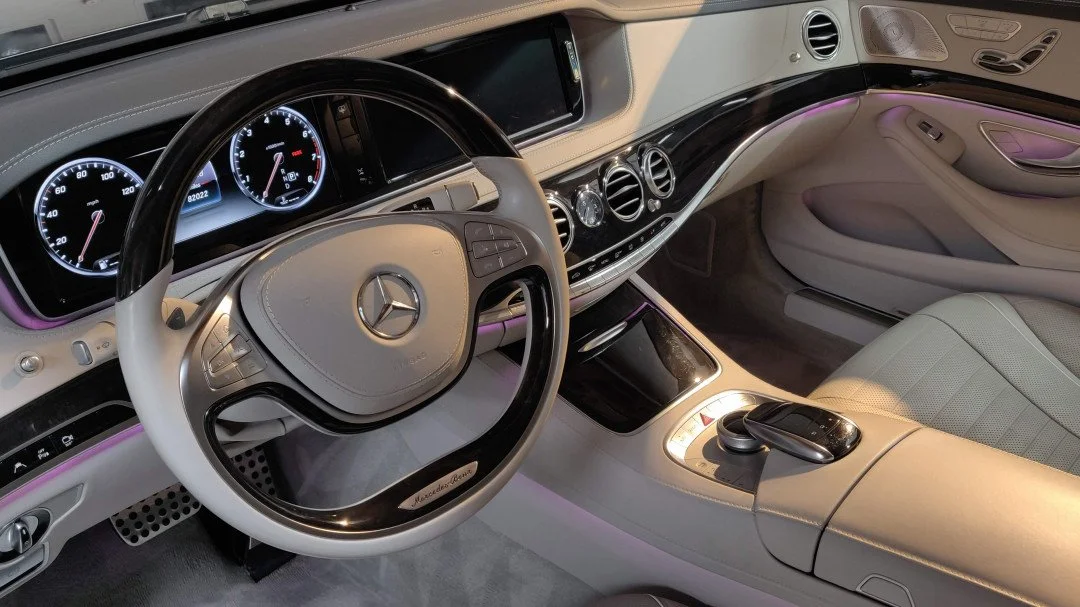 Interior of a Mercedes-Benz car with a beige and black color scheme, digital instrument cluster, and a gear shift controller on the center console.