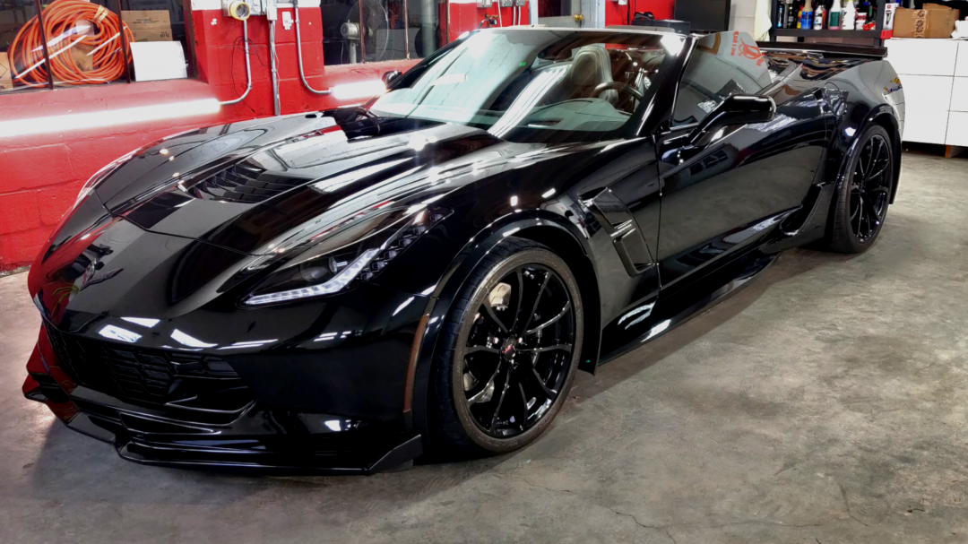 A sleek black Chevrolet Corvette sports car parked inside a garage.
