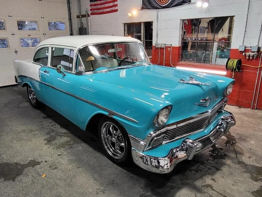A vintage blue and white Chevrolet car inside a garage.