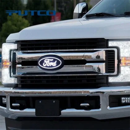 Close-up of the front grille of a white Ford truck, featuring the Ford logo in the center and a Putco emblem in the top left corner.