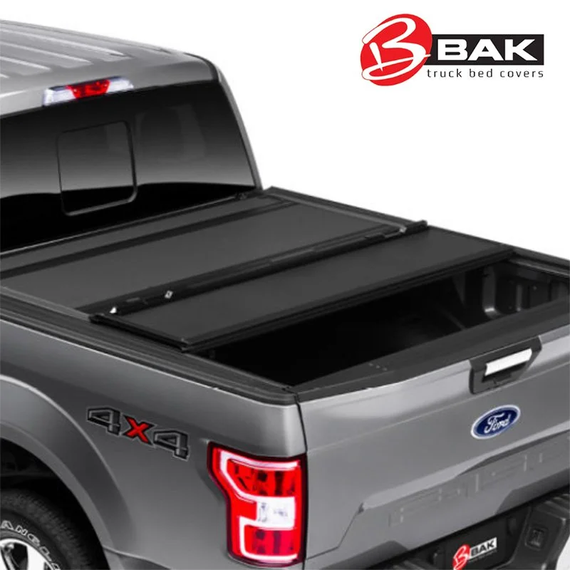 Close-up of a silver Ford truck bed with BAK truck bed cover, logo, and tail light visible.