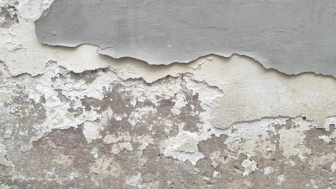 Verwitterte und abblätternde Wand mit verschiedenen Texturen und Farben.