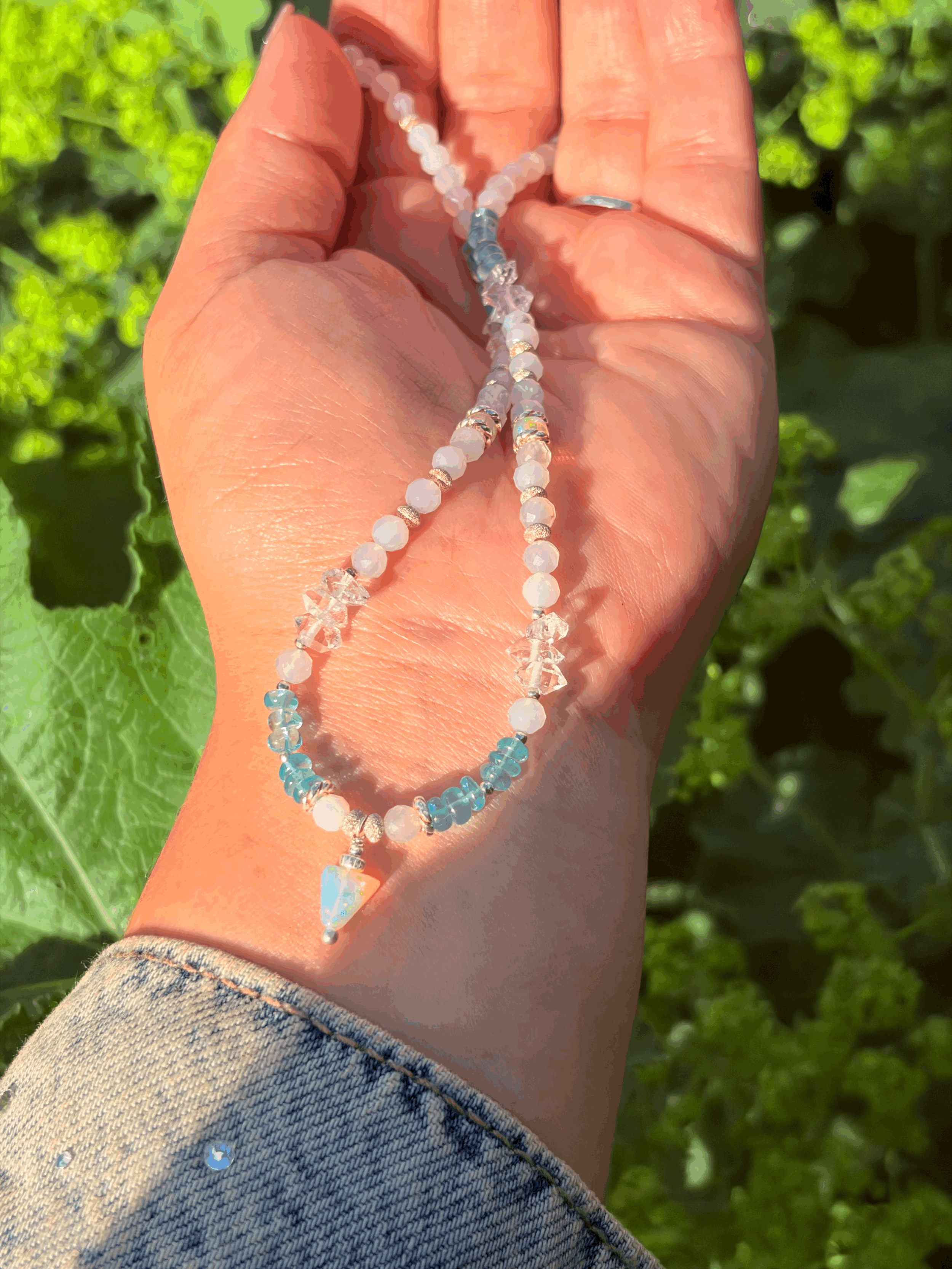 Edelsteinkette AERELIA mit Edelopal-Anhänger und Herkimer-Diamanten auf der Hand