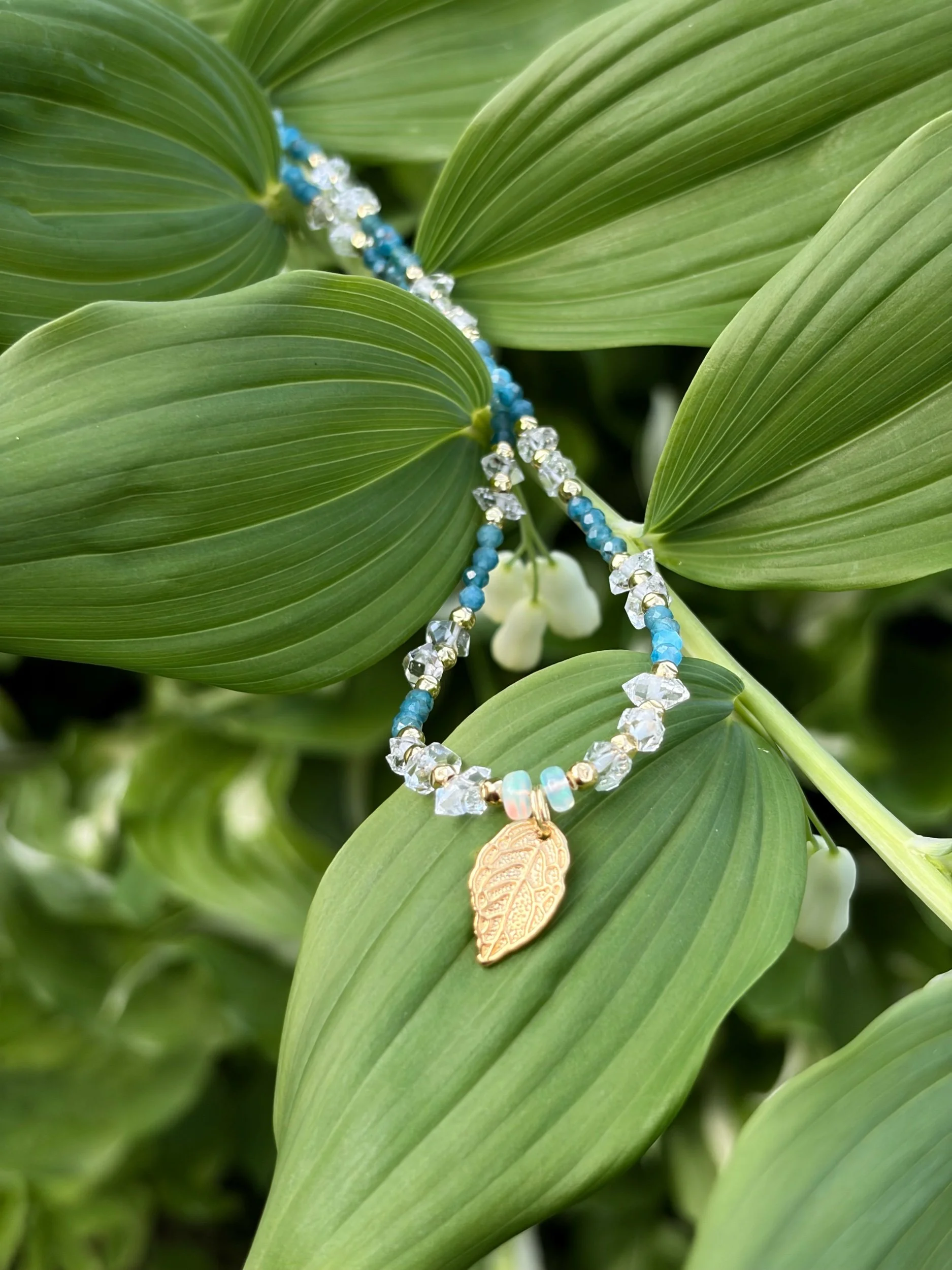 Edelsteinkette AURELIS mit Opal und Apatit auf grünen Pflanzen