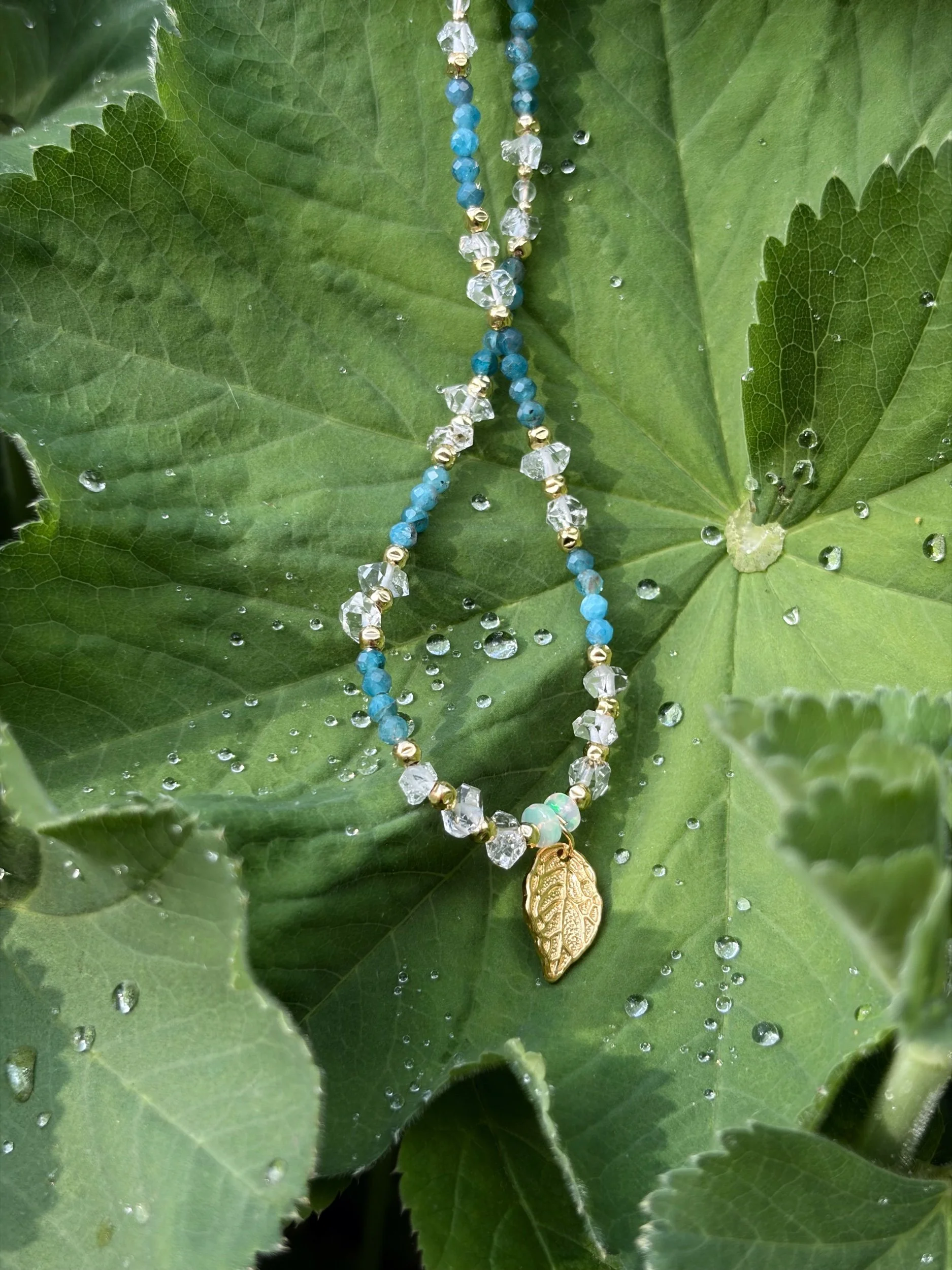 Handgefertigte Opal Kette AURELIS auf natürlichem Pflanzenhintergrund