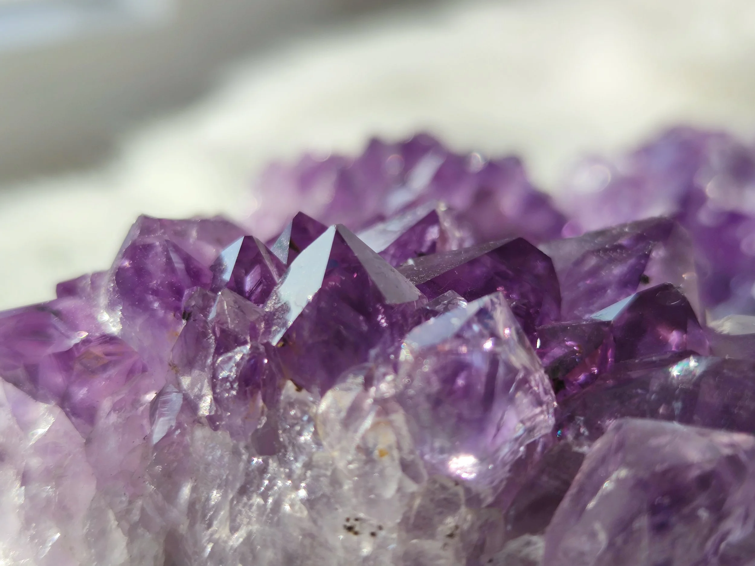 Nahaufnahme von violetten Amethystkristallen mit scharfen, facettierten Spitzen.