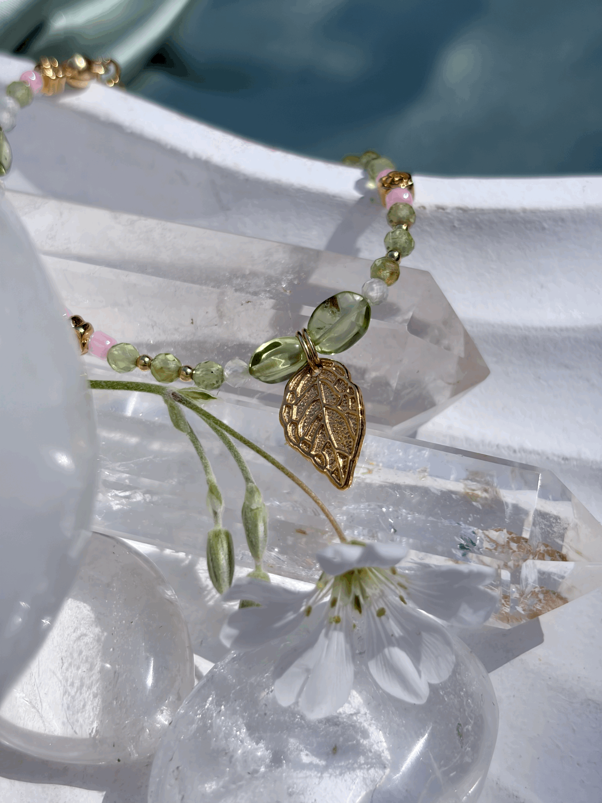 Peridot Armband mit goldenen Blüten auf hellen Kristallen präsentiert