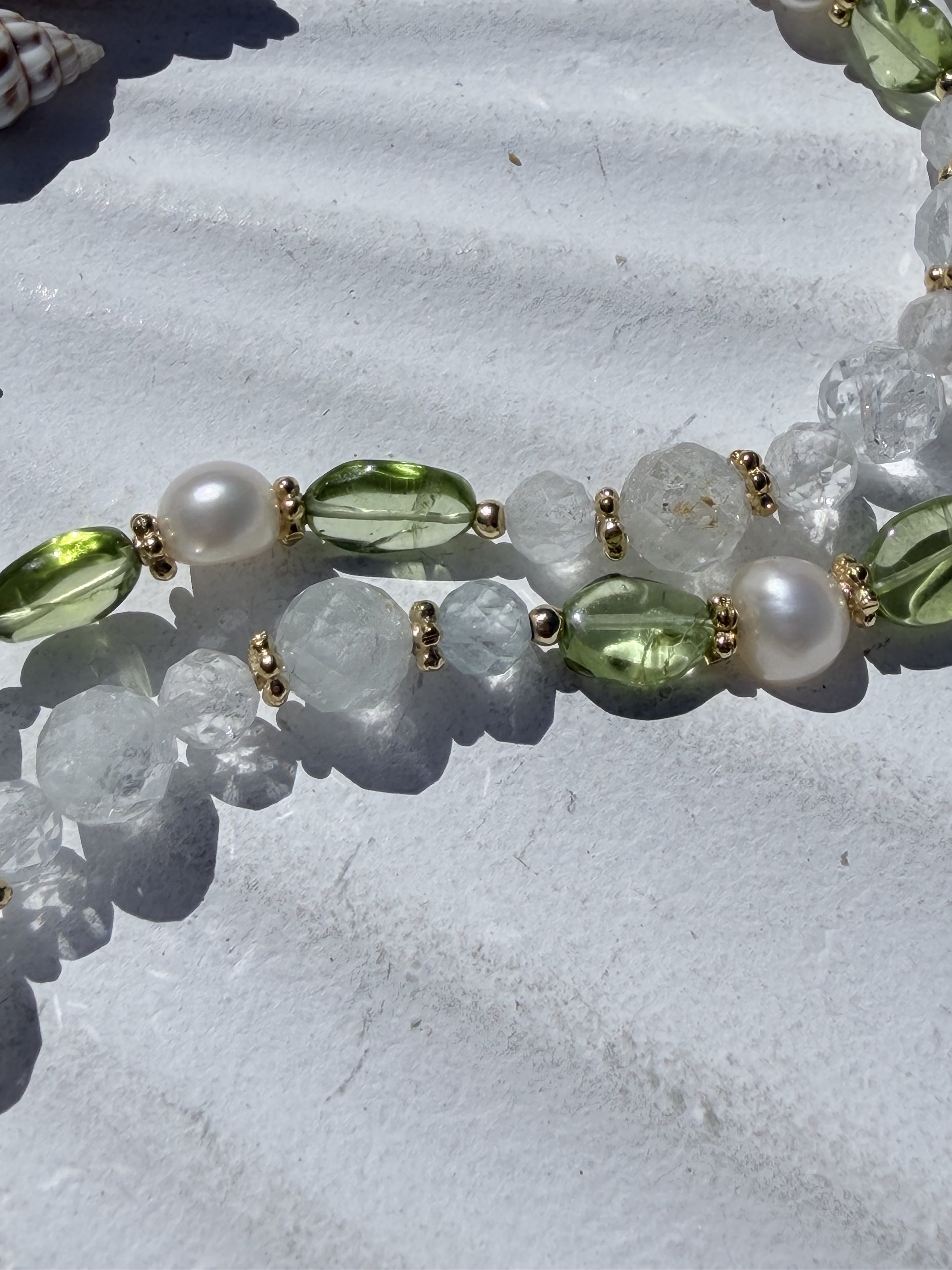 Detailaufnahme der facettierten Natur-Topas Perlen und des leuchtend grünen Peridots der Halskette MIREYA