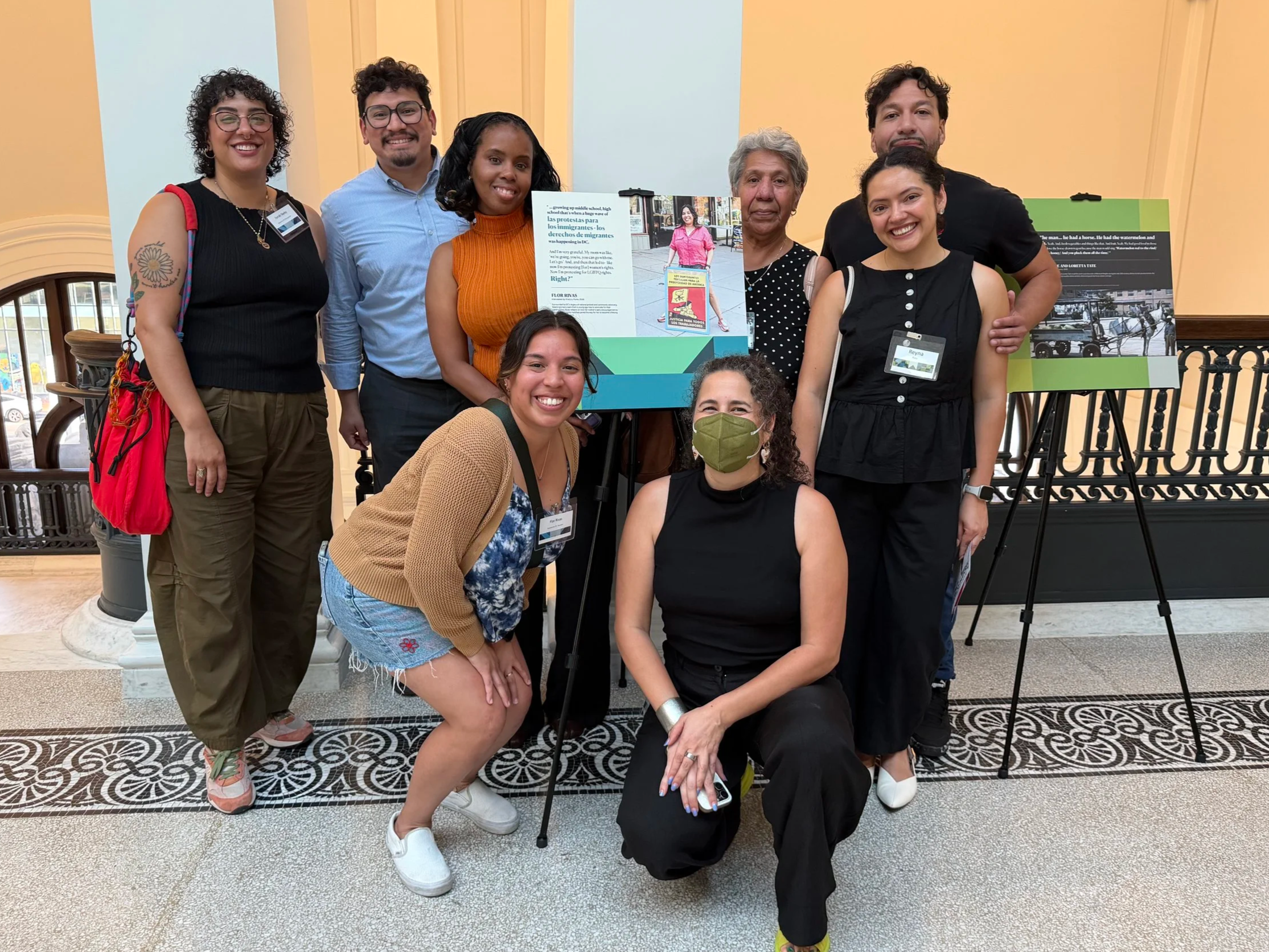 Narrator Flor Rivas, photographer Farrah Skeiky, and oral historian Kristy L. posing with friends beside a preview of Rivas's panel at the opening reception.