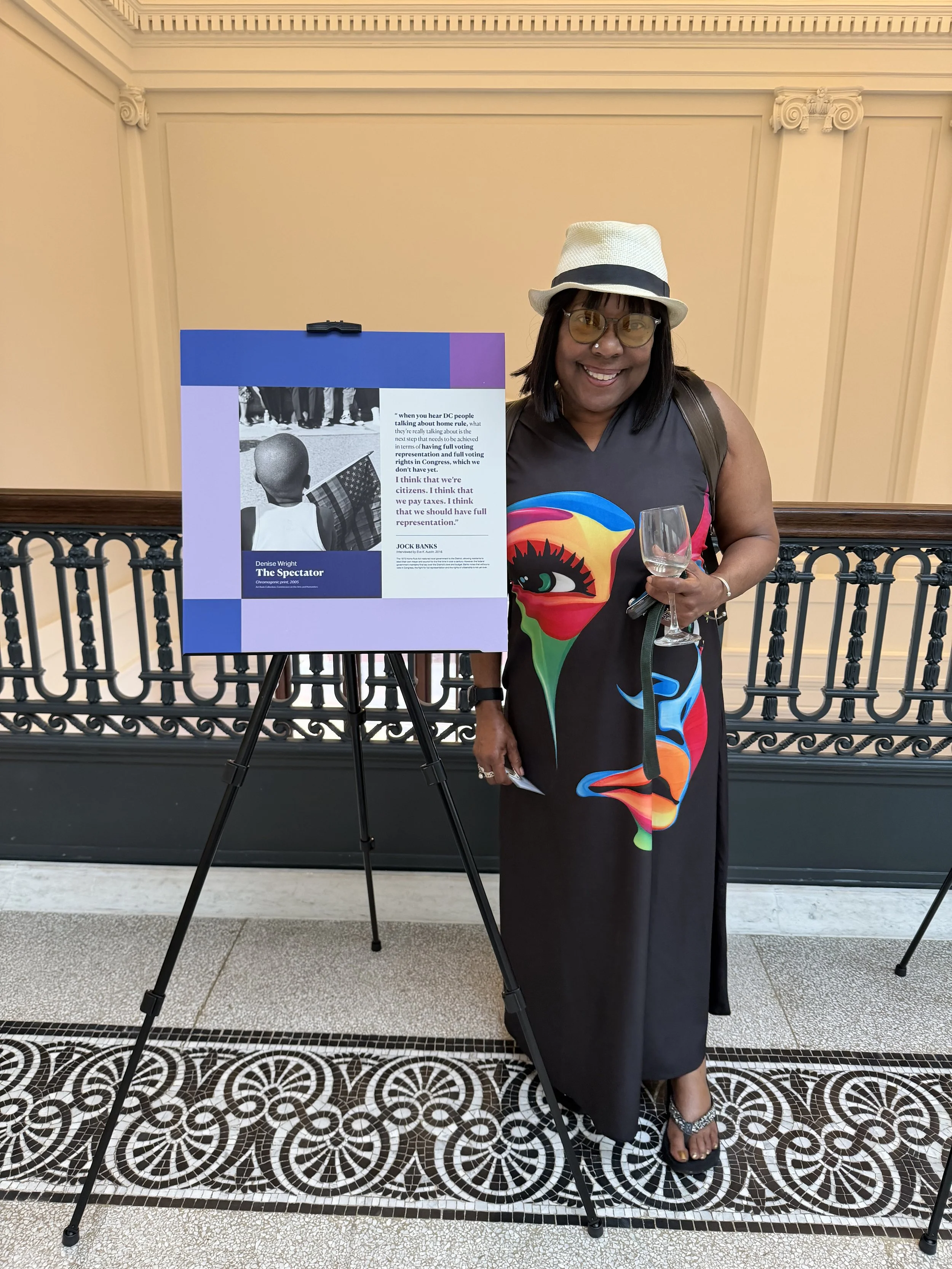Artist Denise Wright posing beside a panel preview featuring her photograph, The Spectator (2005), courtesy of the DCCAH Art Bank Collection.