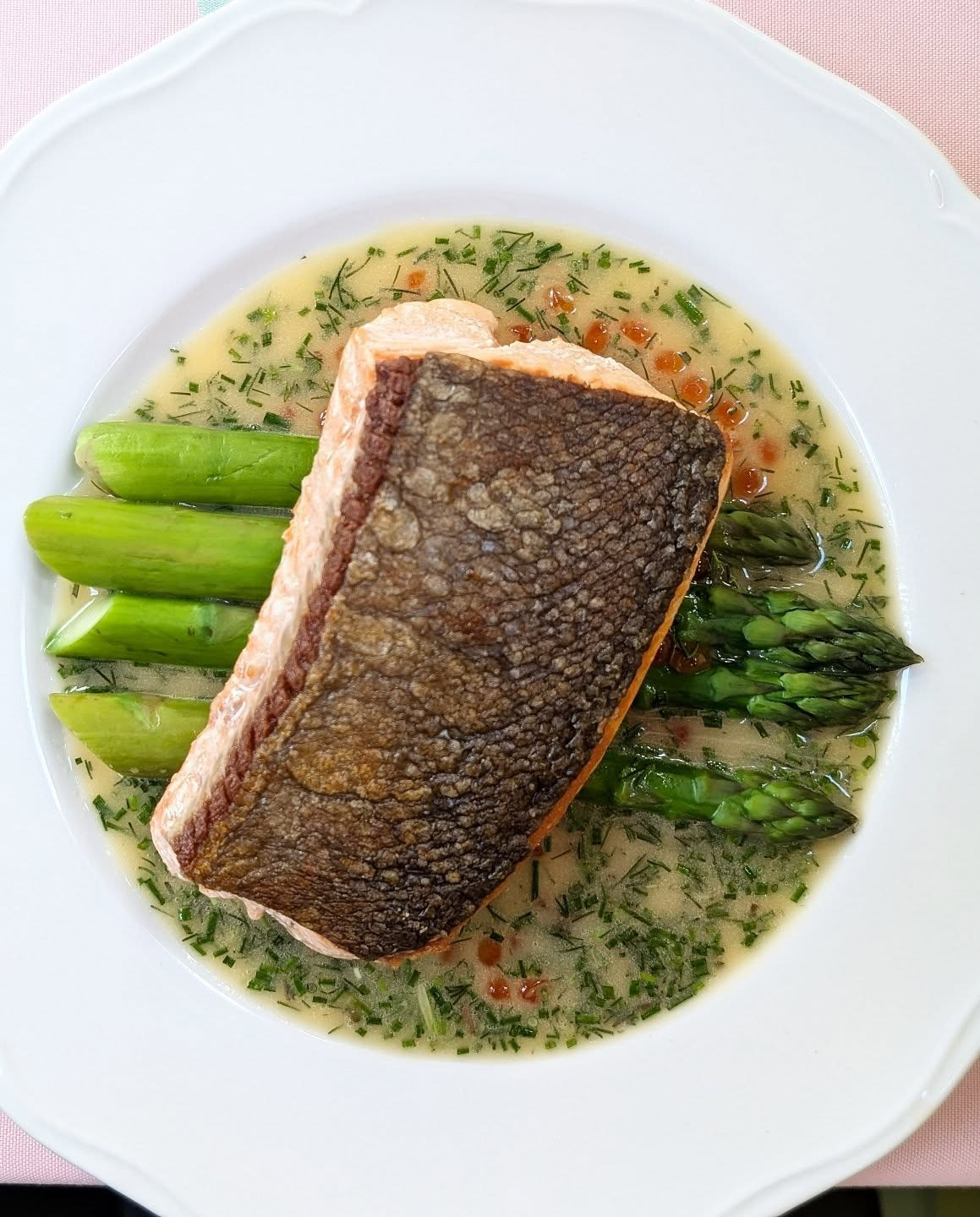 Fresh caught wild salmon sits atop locally sourced organic asparagus in an elegant dish to be enjoyed indoors or on the patio.