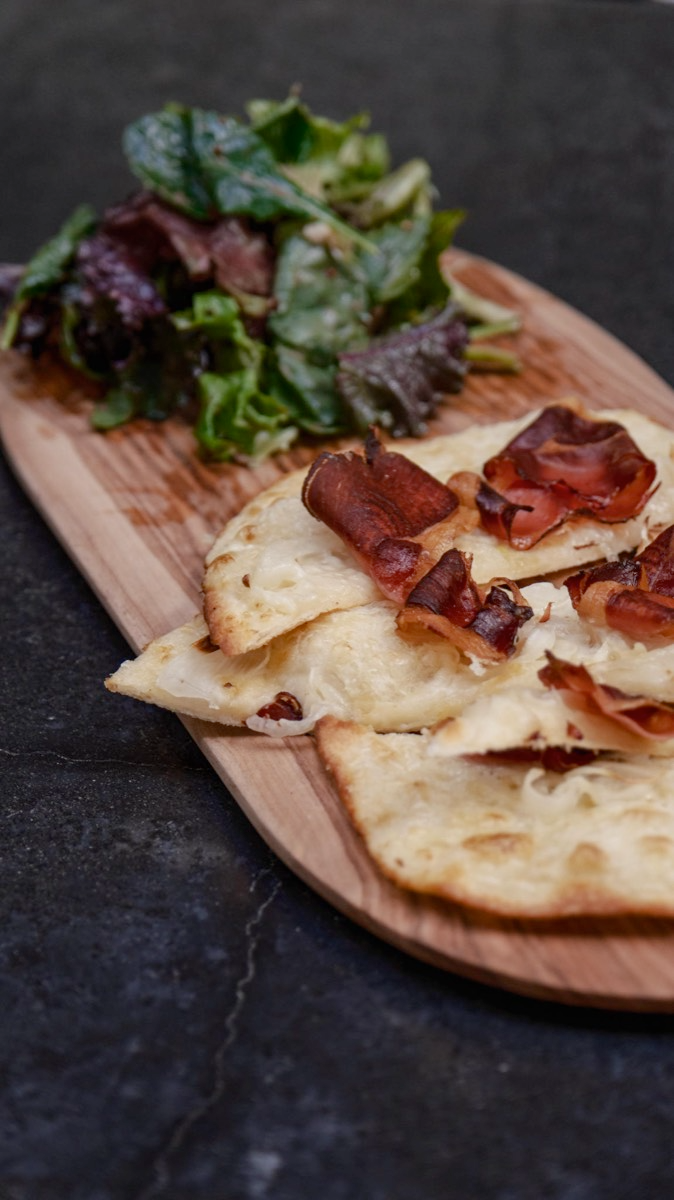 Tarte flambée or German Pizza featuring the traditional and authentic speck and onion toppings. Cooked in the wood fired oven and with the option of vegan, vegetarian, gluten free and dairy free. Available for Happy Hour.
