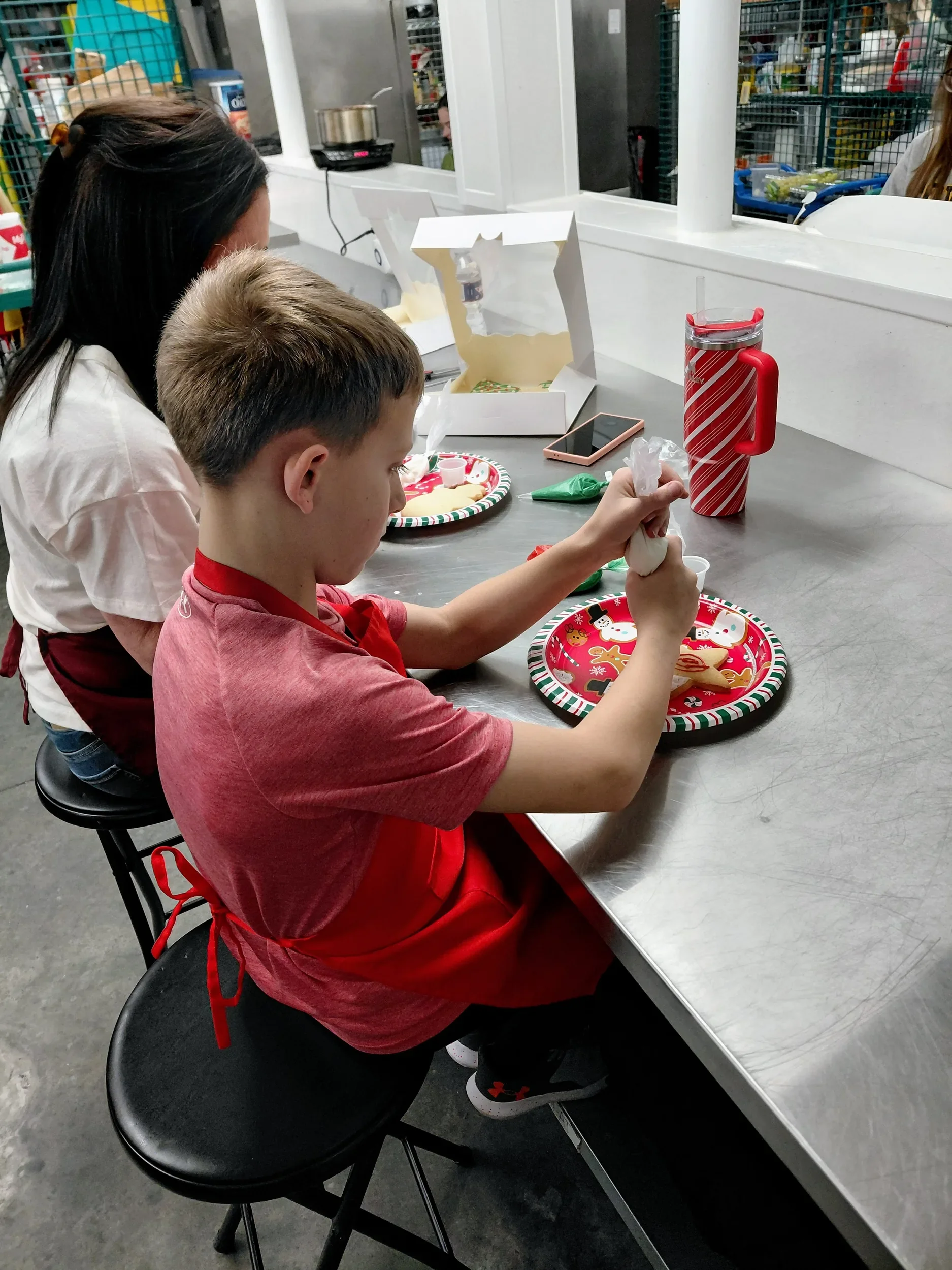 Child and mother decorating holiday sugar cookies with icing during a cooking class