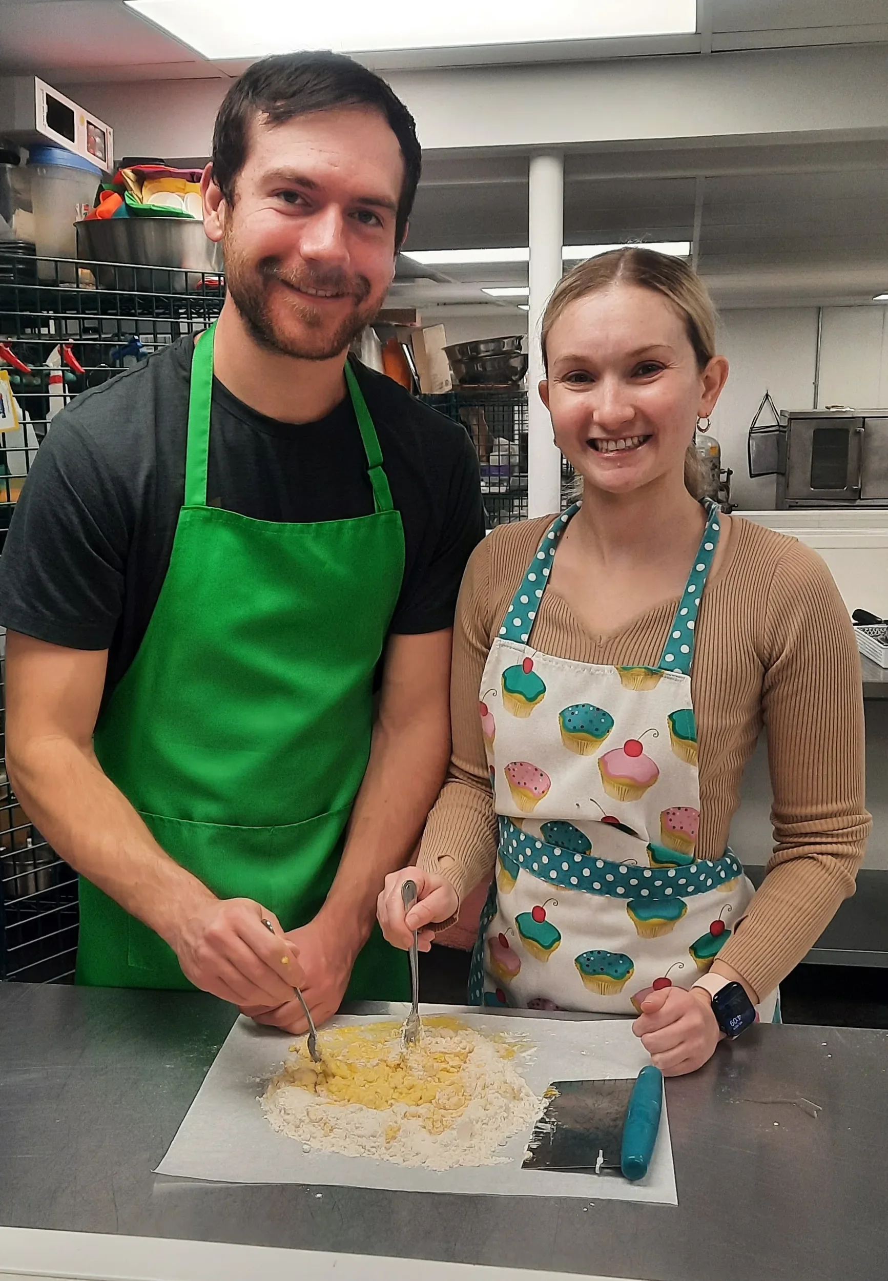 A couple holding a fork into flour and eggs while making pasta with smiles during a private lesson for two cooking class