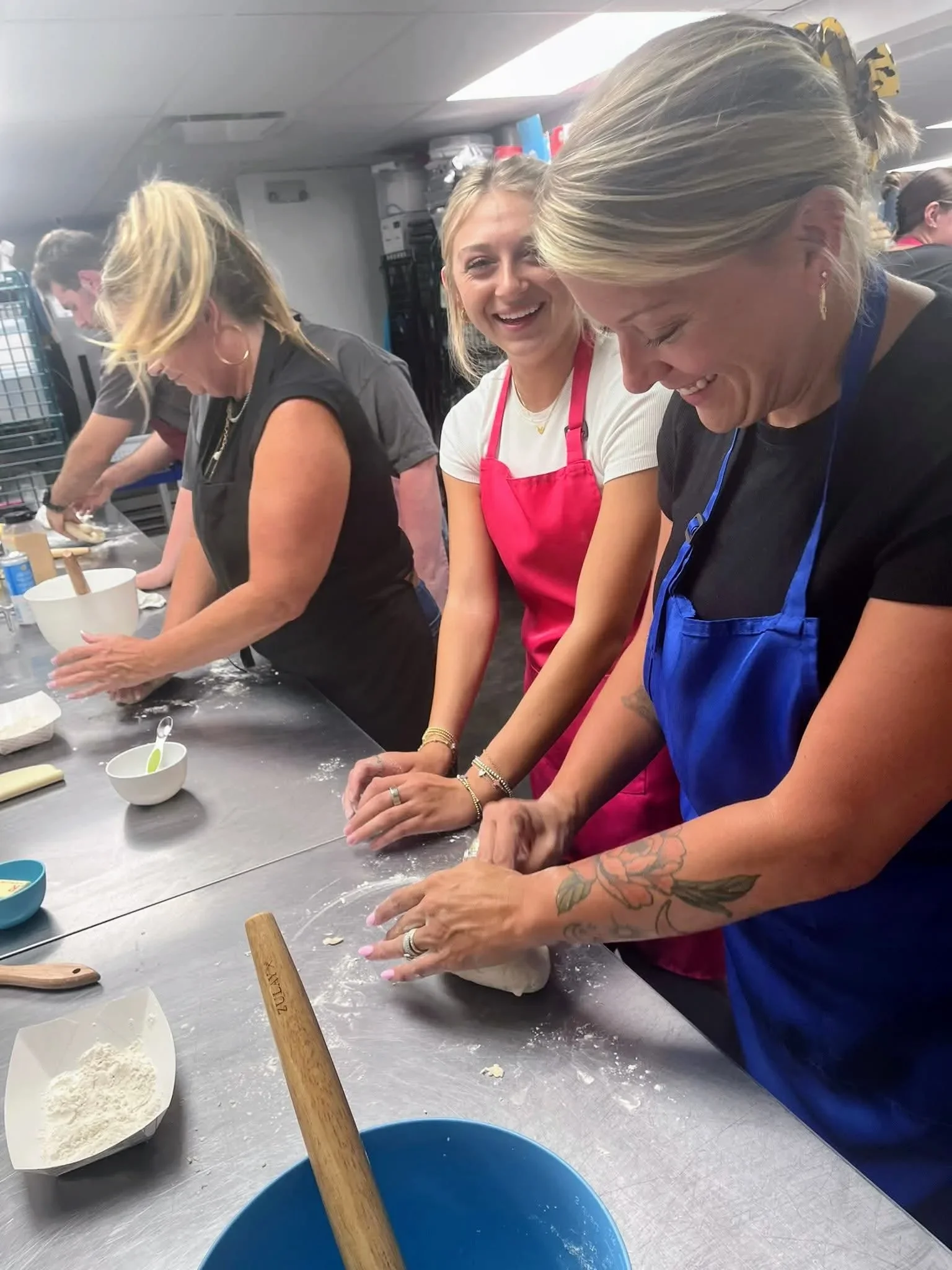 Three women laughing while shaping dough by hand at an adult cooking class