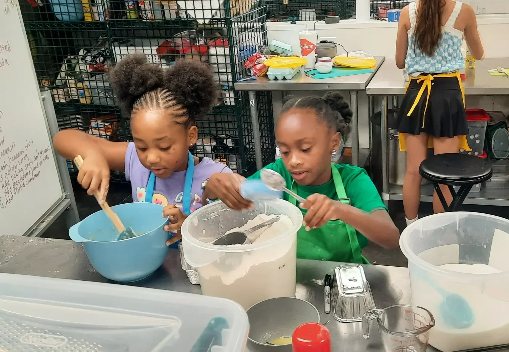 Two young campers working together to measure and mix ingredients for banana bread during camp.