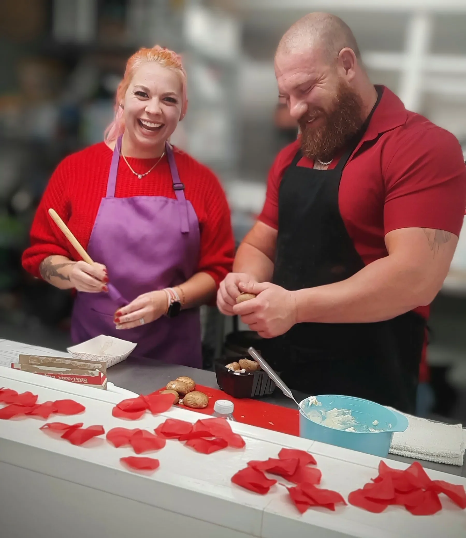 A couple laughing while making stuffed mushrooms at a Cooking Date Night class.