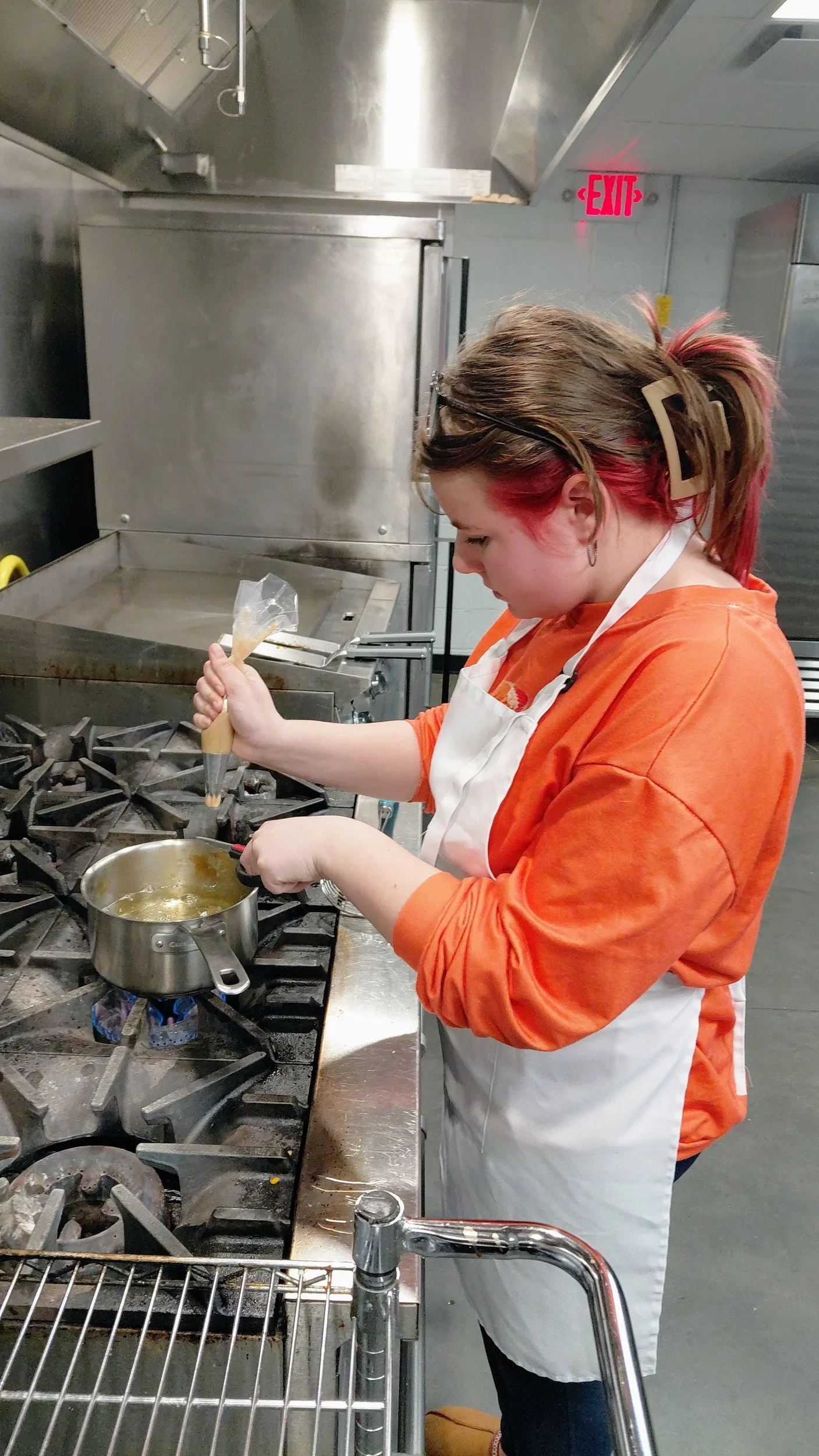 A teen squeezing out her Churros to fry during the teen cooking class.