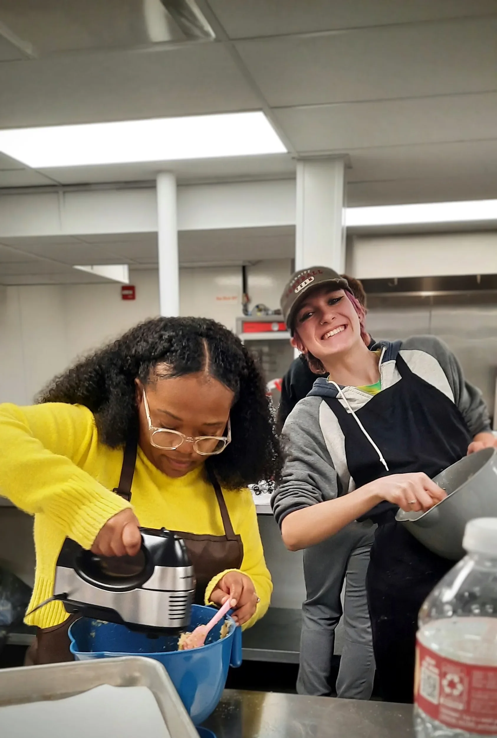 Two students from the cooks in the making class preparing their cookies one smiling one focused